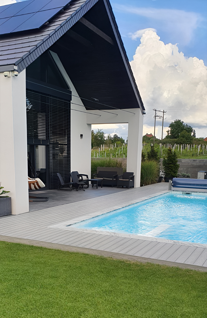 BRUGGAN Multicolor grey composite decking around a modern outdoor swimming pool and terrace in a landscaped private garden