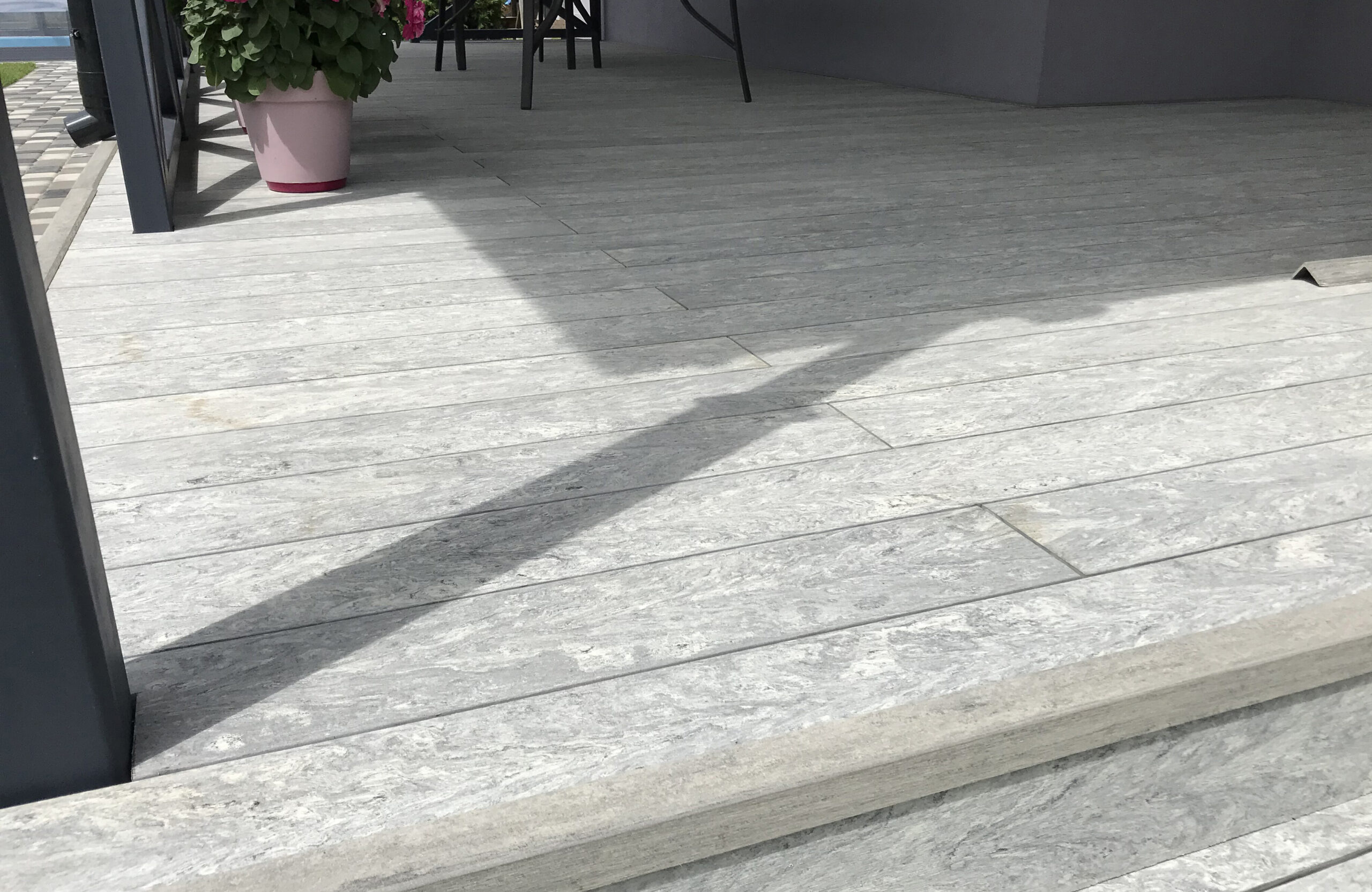 BRUGGAN Multicolor grey decking used for a stylish covered patio with integrated stairs and decorative railings.