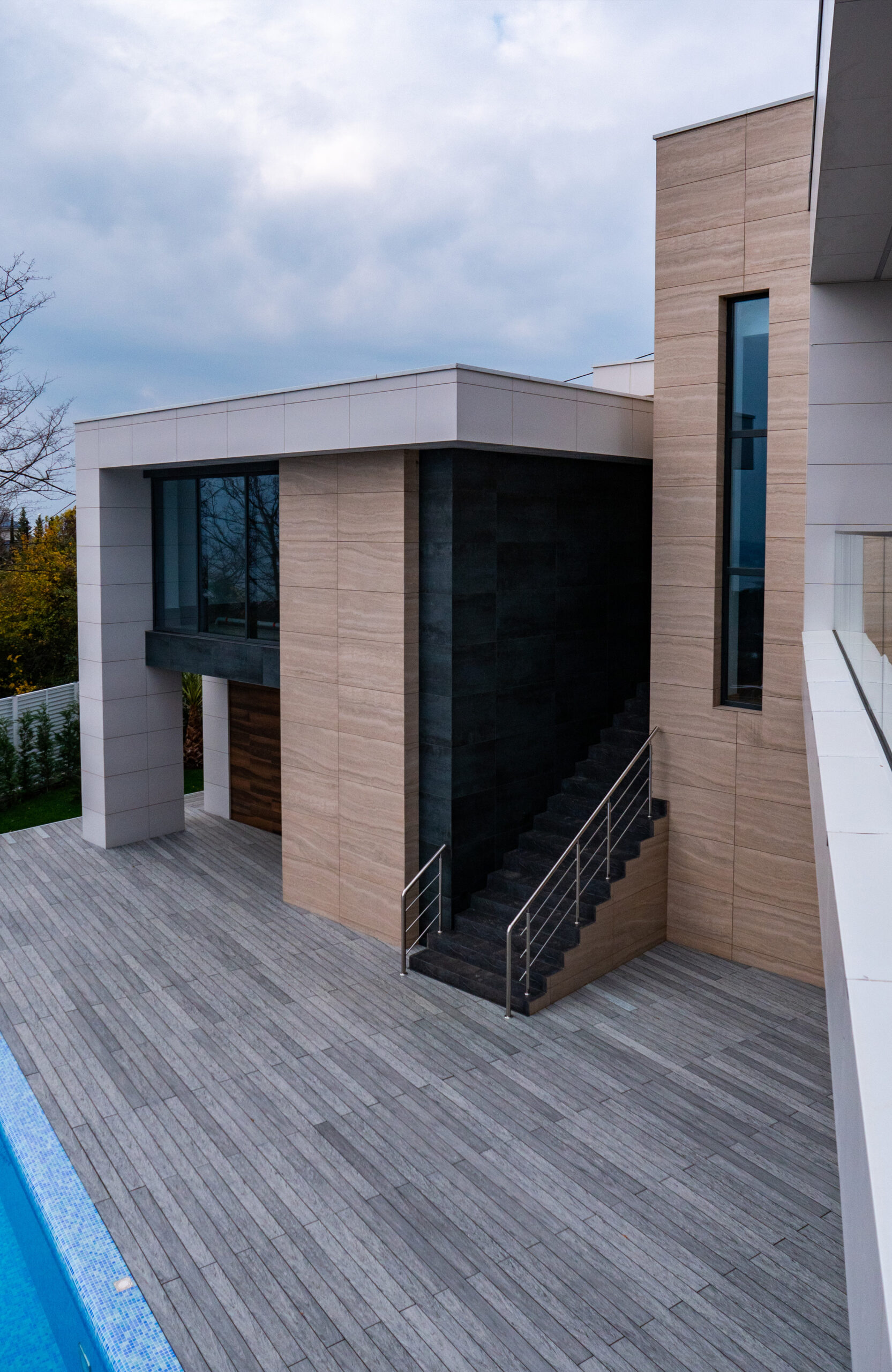 Large grey composite decking terrace surrounding a swimming pool at a modern residence