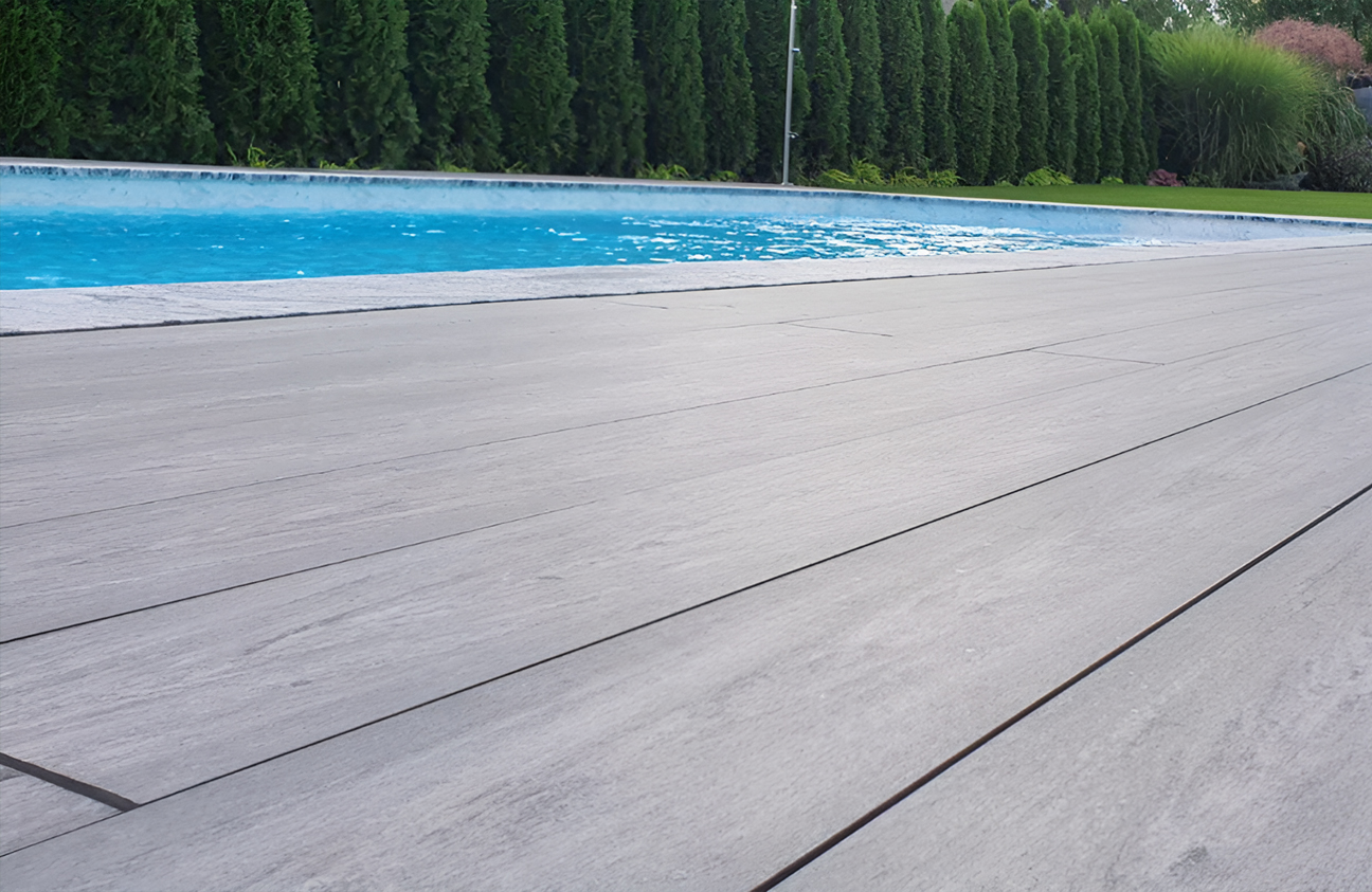 BRUGGAN Multicolor grey composite decking around a modern outdoor swimming pool and terrace in a landscaped private garden
