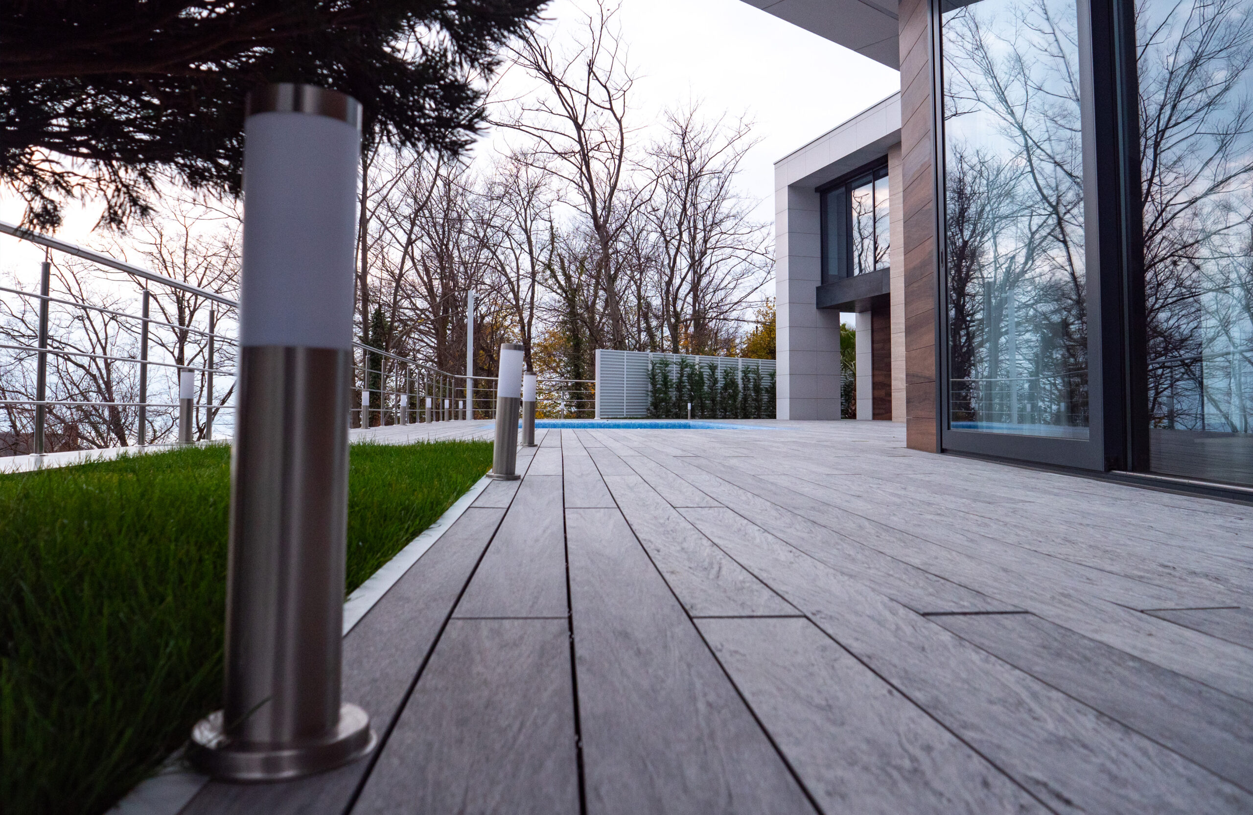 Close-up view of Bruggan Multicolor Grey composite decking beside a modern house and pool
