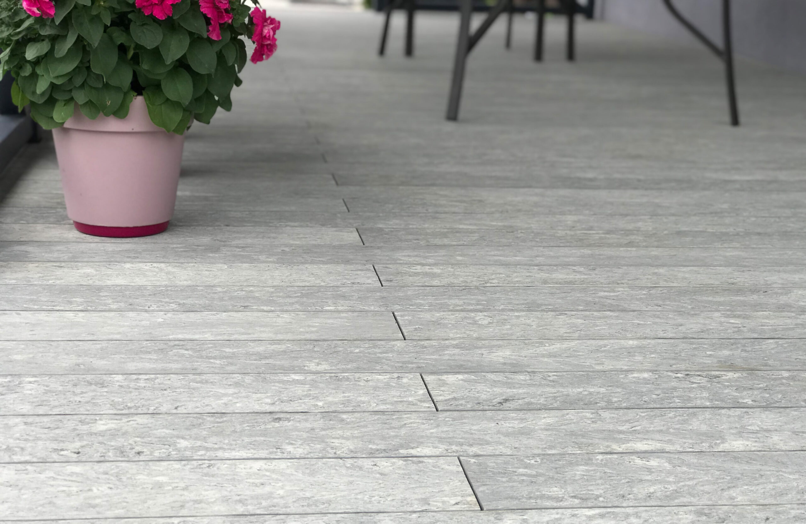 BRUGGAN Multicolor grey decking used for a stylish covered patio with integrated stairs and decorative railings.
