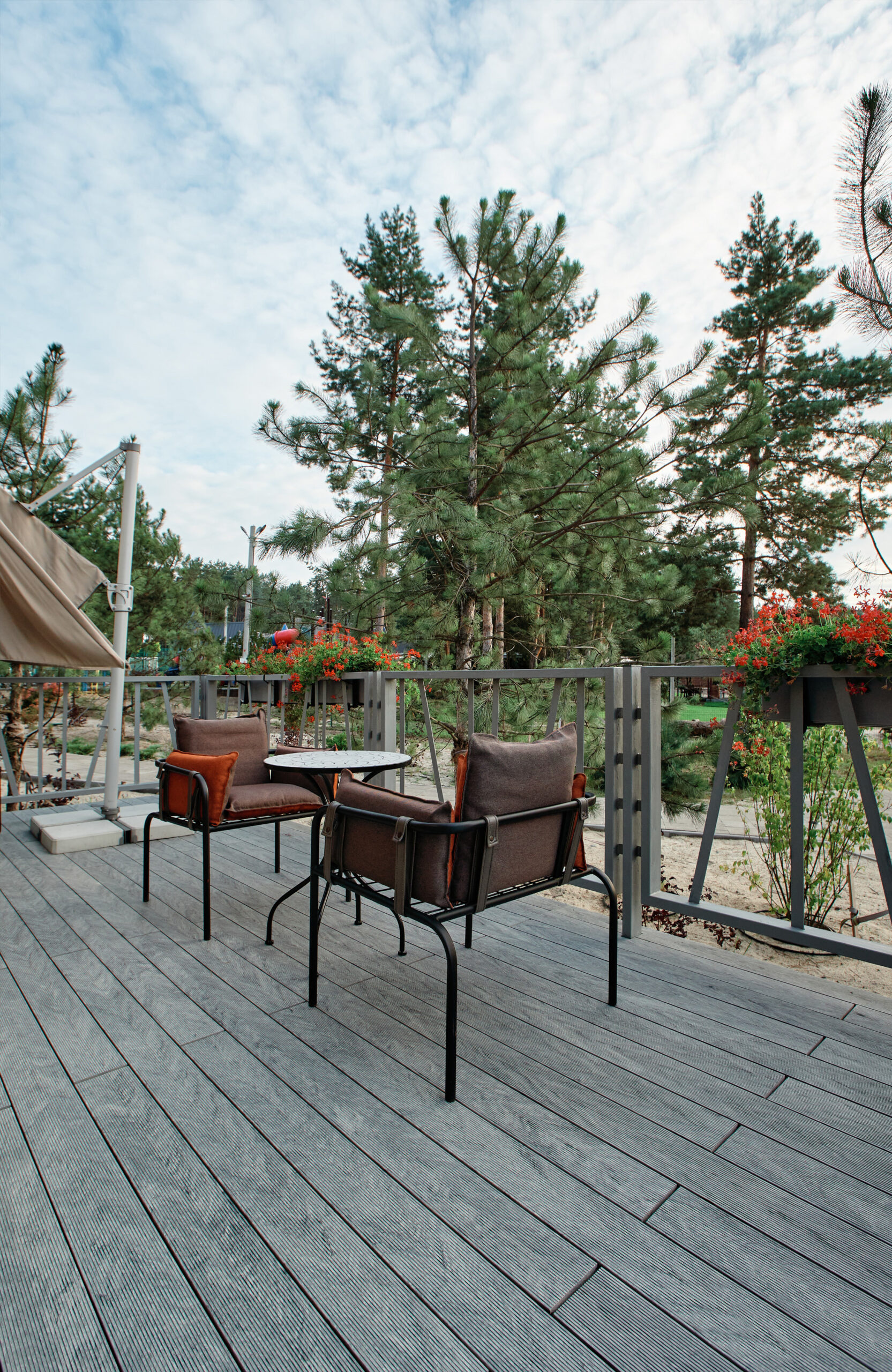 Grey BRUGGAN Multicolor composite decking on a modern outdoor terrace surrounded by pine trees