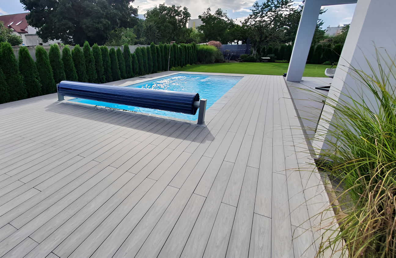 BRUGGAN Multicolor grey composite decking around a modern outdoor swimming pool and terrace in a landscaped private garden