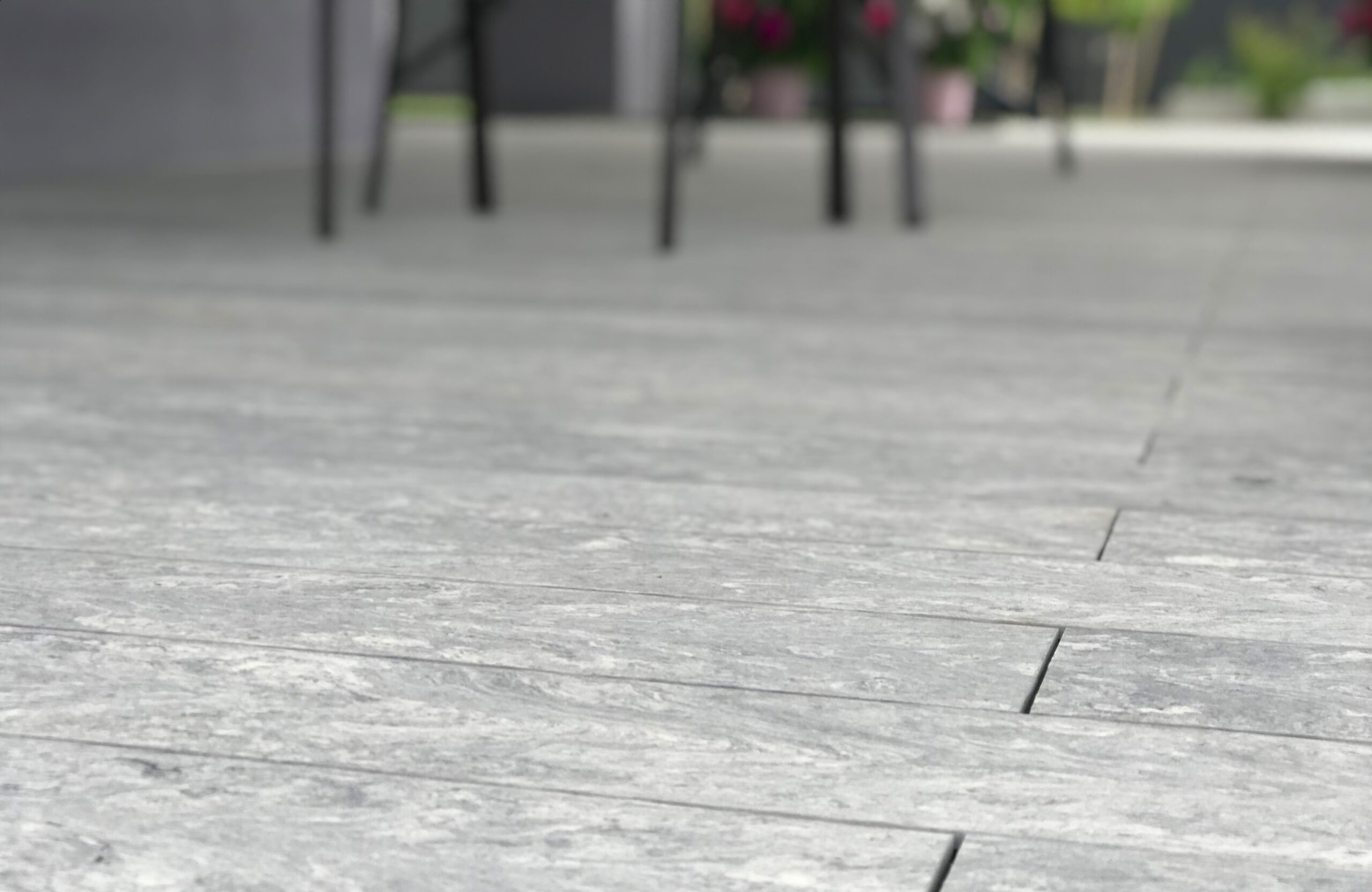 BRUGGAN Multicolor grey decking used for a stylish covered patio with integrated stairs and decorative railings.