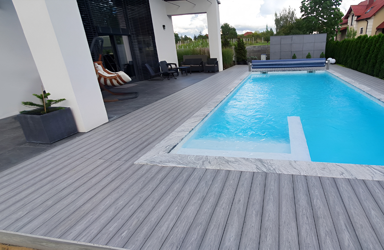 BRUGGAN Multicolor grey composite decking around a modern outdoor swimming pool and terrace in a landscaped private garden