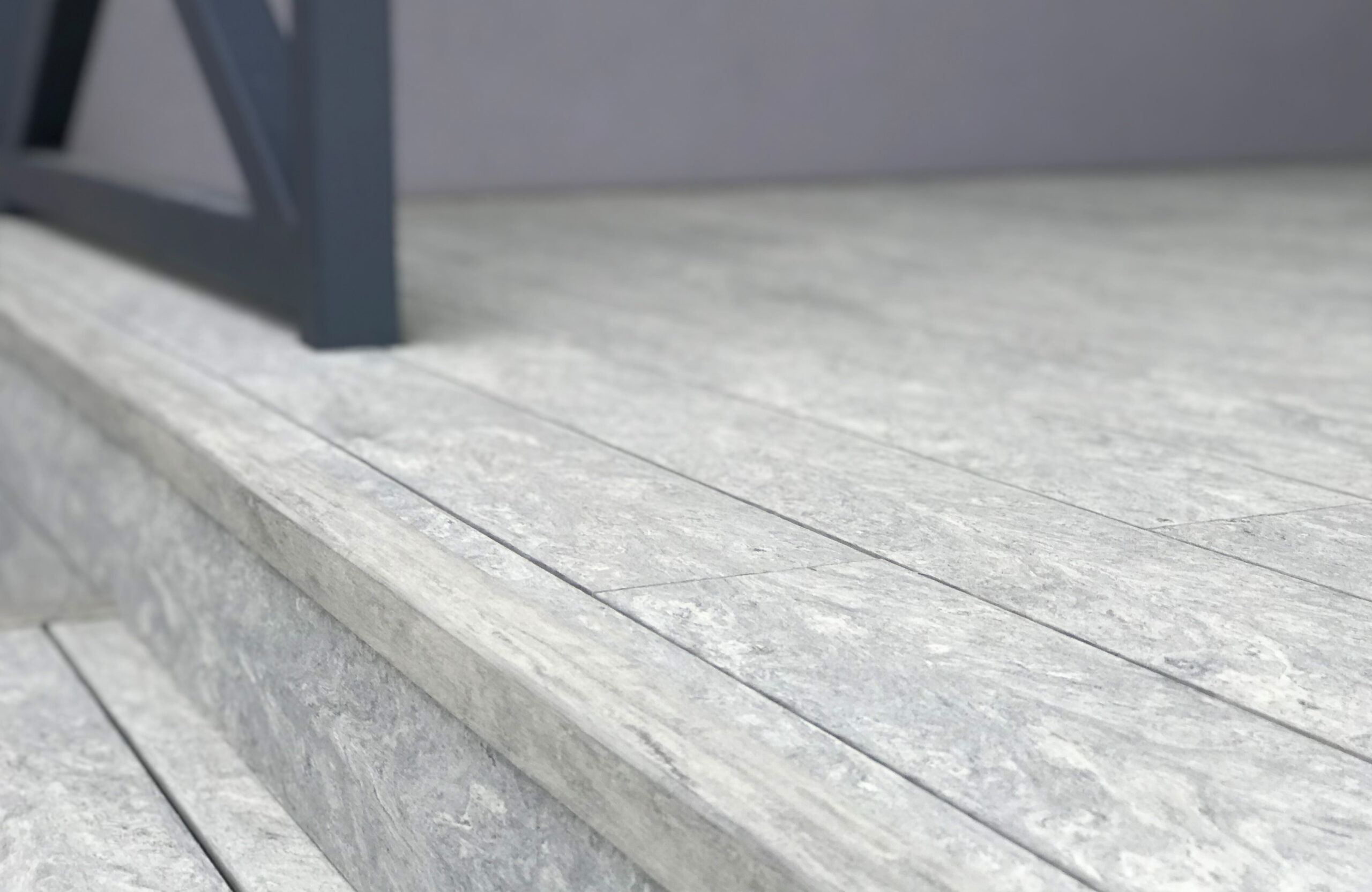 BRUGGAN Multicolor grey decking used for a stylish covered patio with integrated stairs and decorative railings.