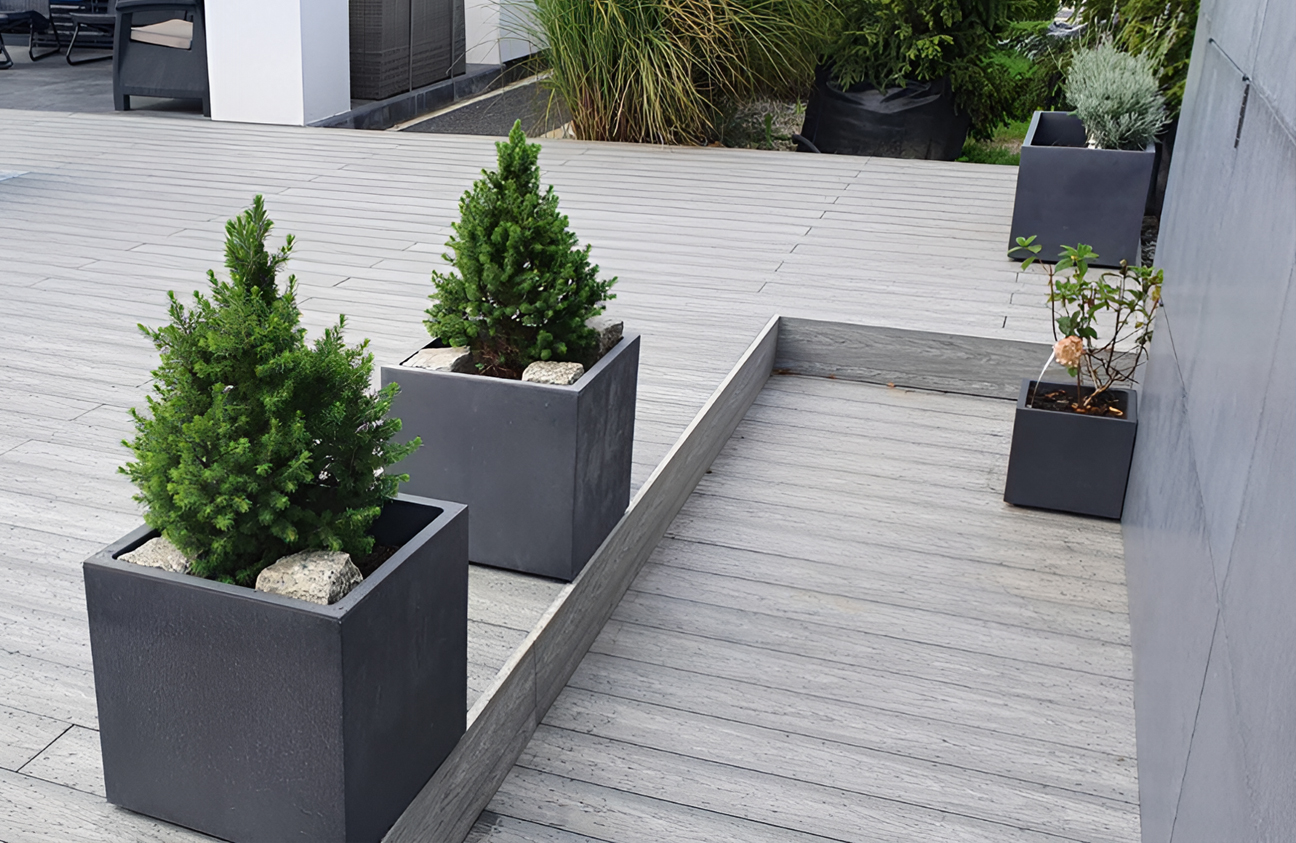 BRUGGAN Multicolor grey composite decking around a modern outdoor swimming pool and terrace in a landscaped private garden