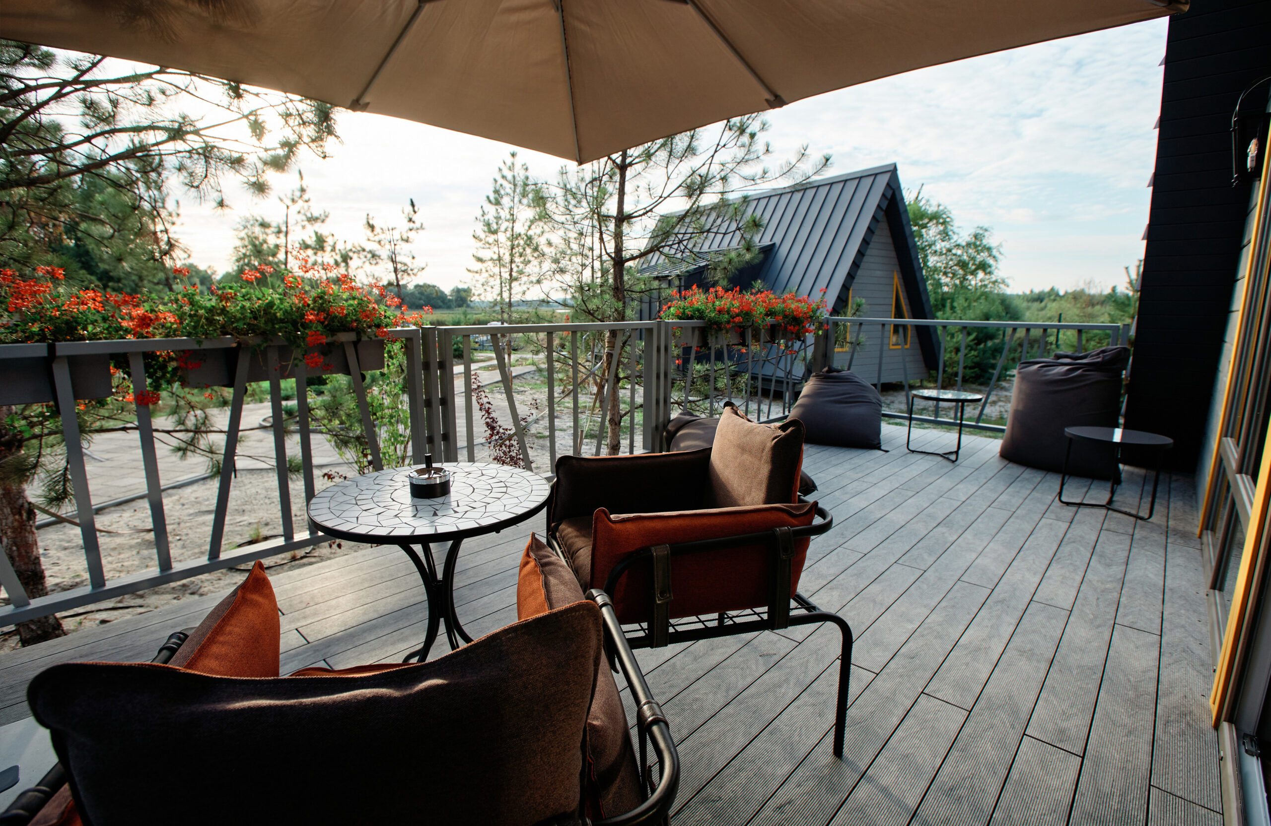 Grey BRUGGAN Multicolor composite decking on a modern outdoor terrace surrounded by pine trees