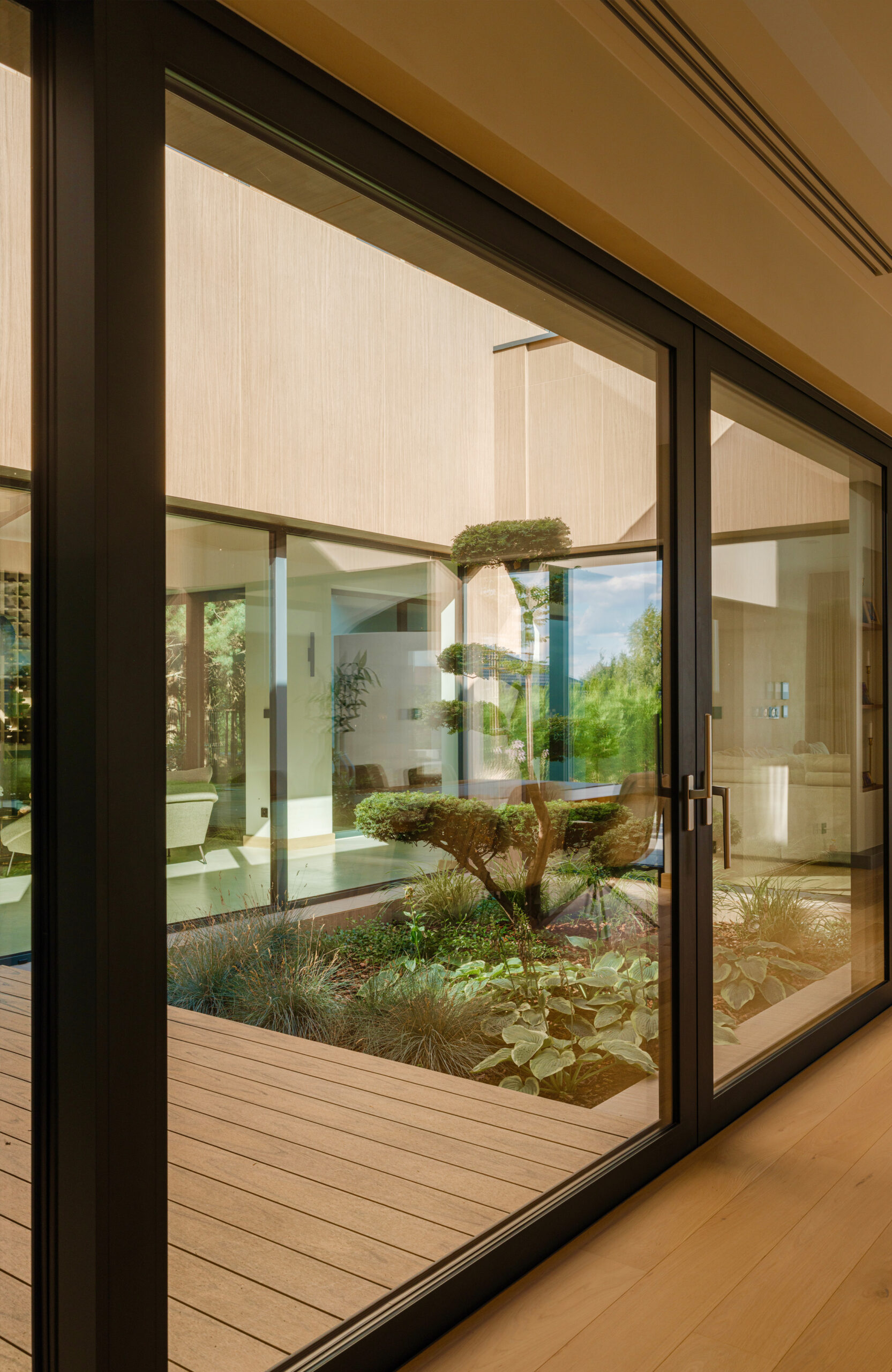 Sand-colored BRUGGAN Multicolor composite decking in a contemporary inner courtyard with panoramic glazing