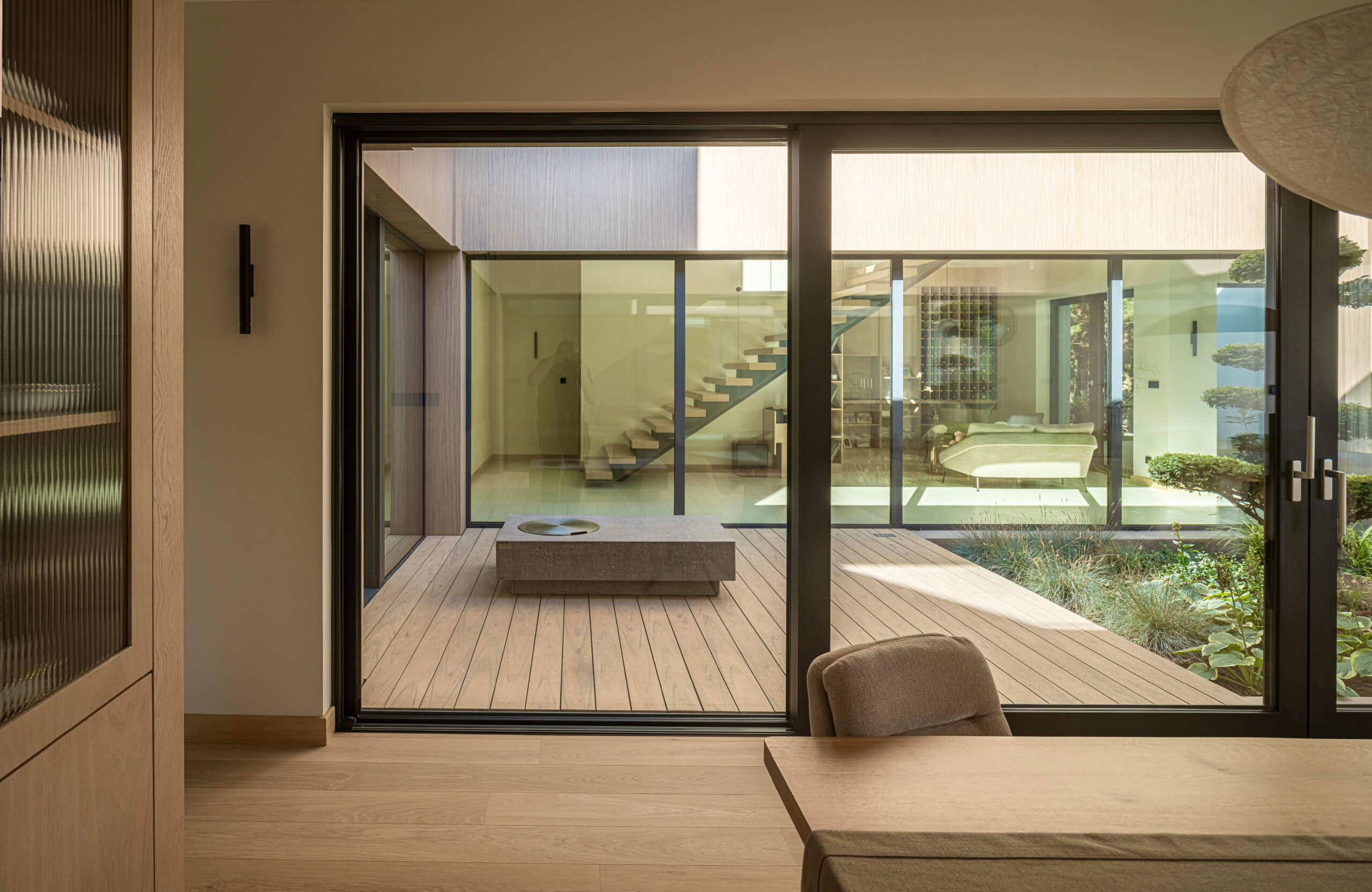Sand-colored BRUGGAN Multicolor composite decking in a contemporary inner courtyard with panoramic glazing