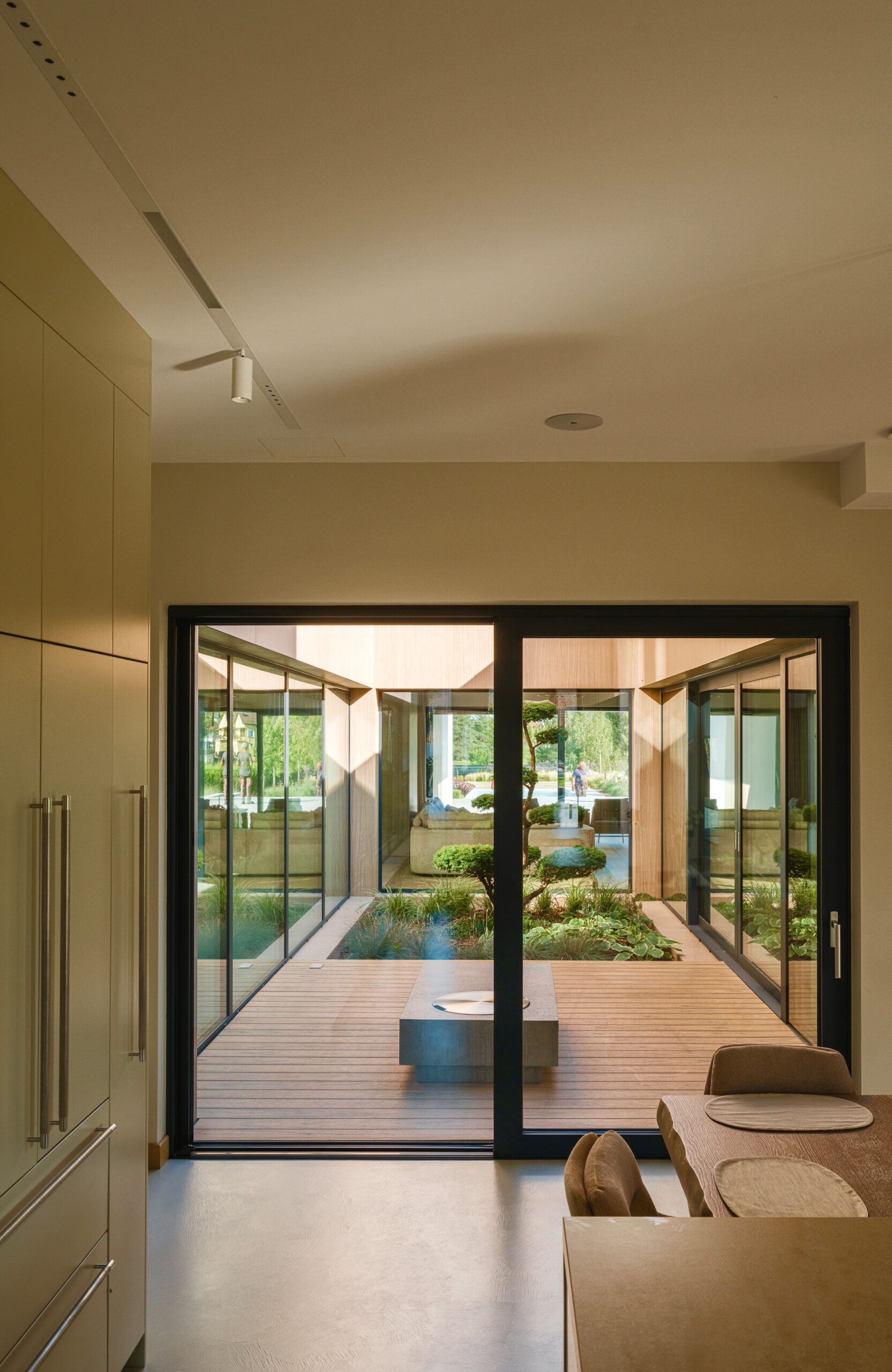 Sand-colored BRUGGAN Multicolor composite decking in a contemporary inner courtyard with panoramic glazing