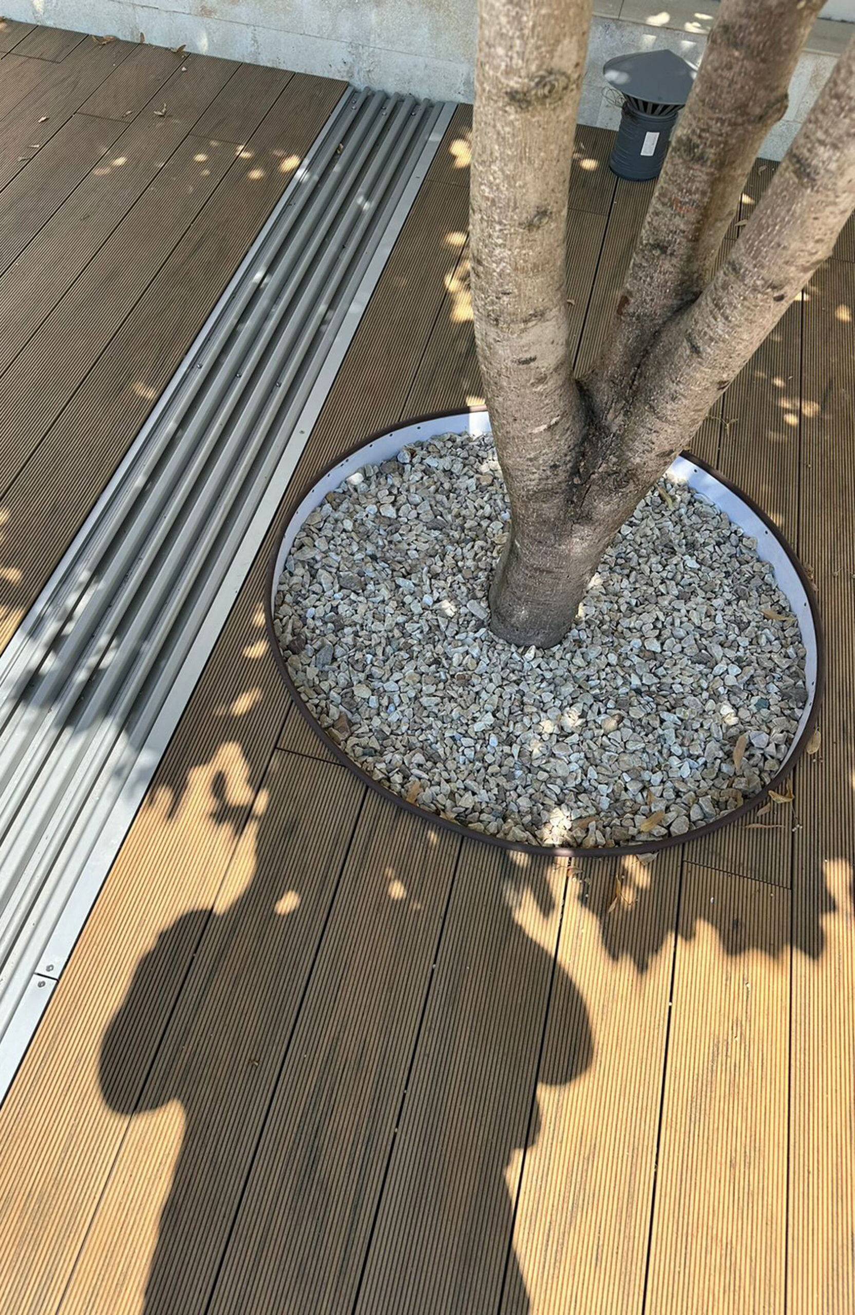 Sand-colored BRUGGAN Multicolor composite decking surrounding a garden pool with trees and lawn