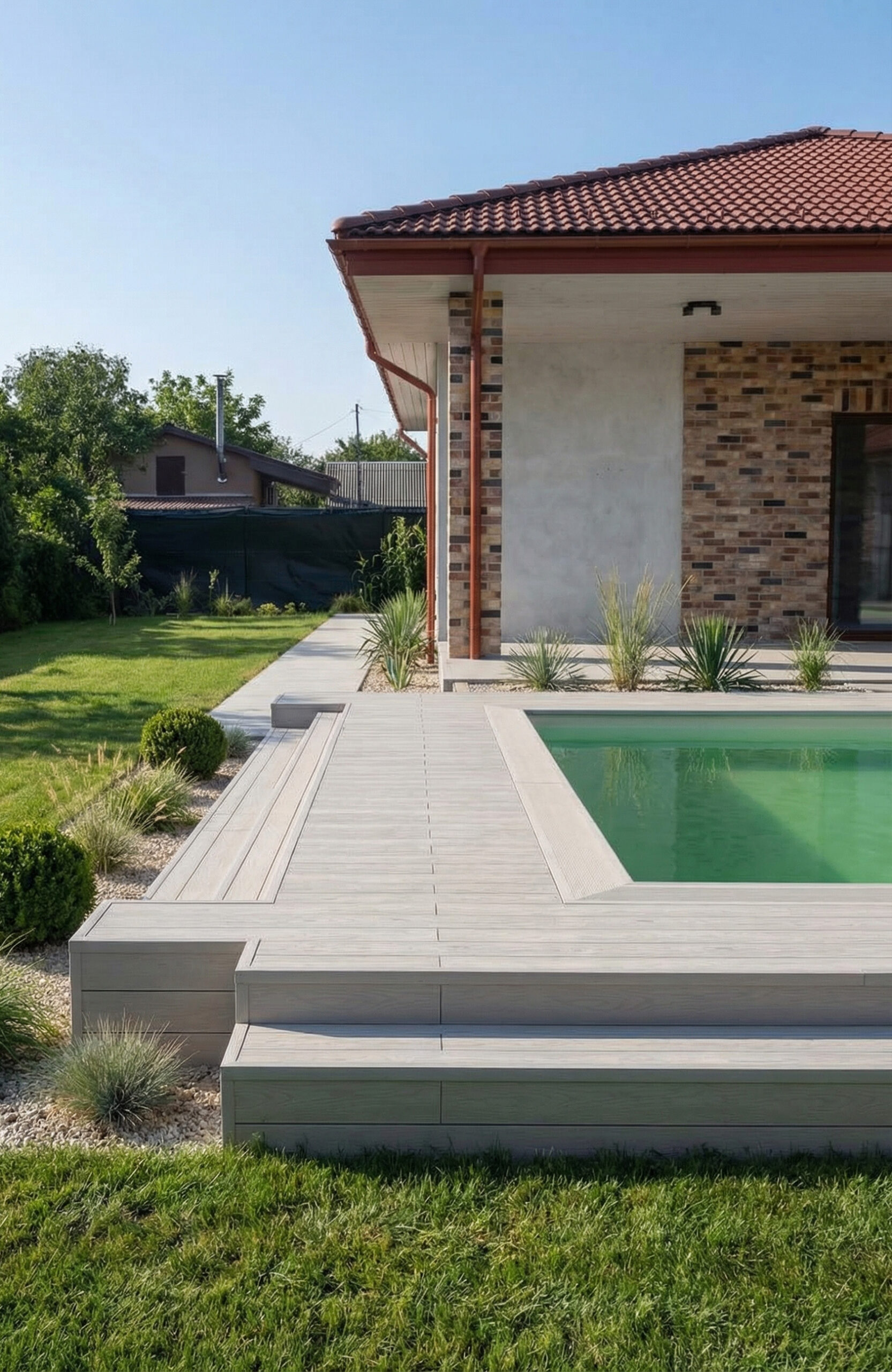 Light composite decking around a swimming pool with matching wide stairs