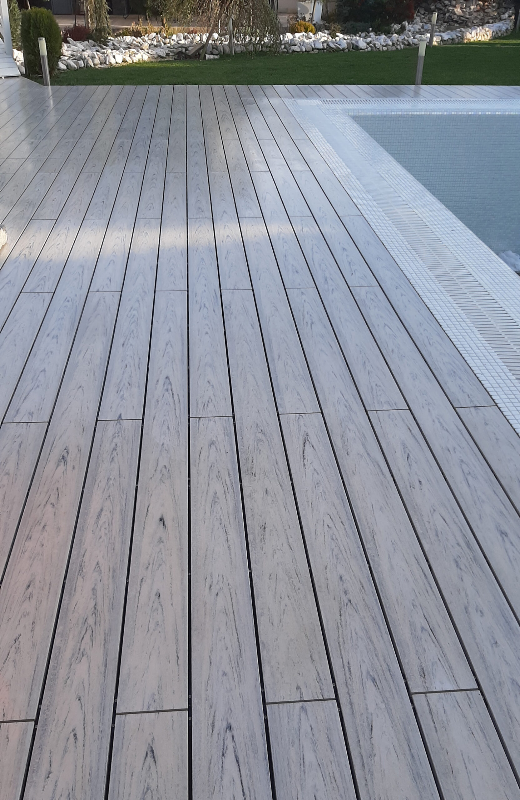 Modern pool terrace finished with light grey wood-effect composite decking
