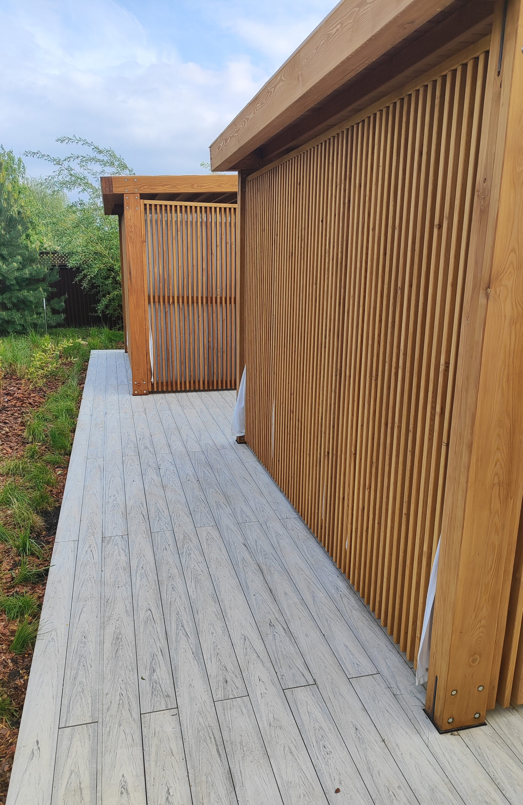 Modern lakeside terrace with light composite decking, lounge areas and glass railing