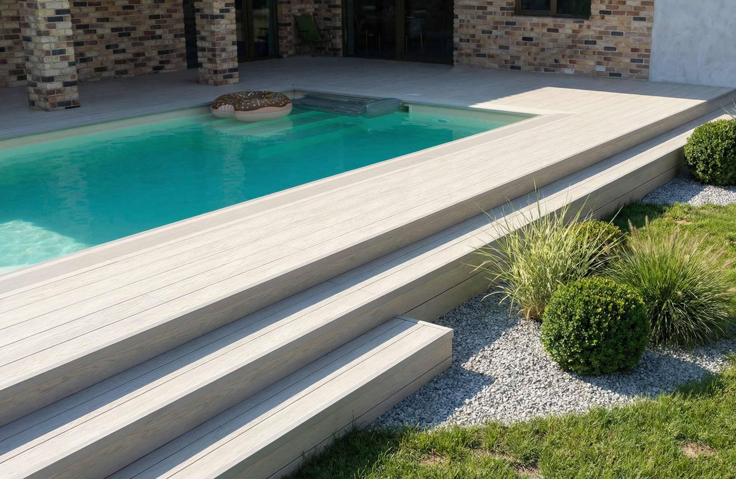Light composite decking around a swimming pool with matching wide stairs