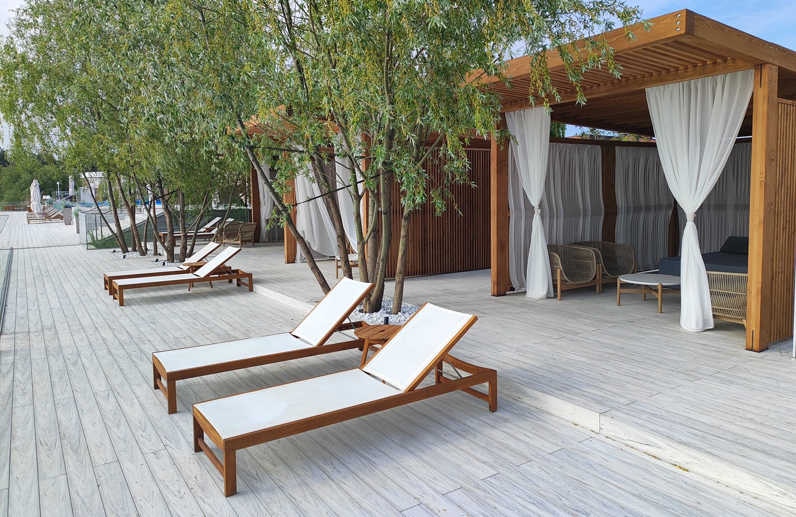Modern lakeside terrace with light composite decking, lounge areas and glass railing