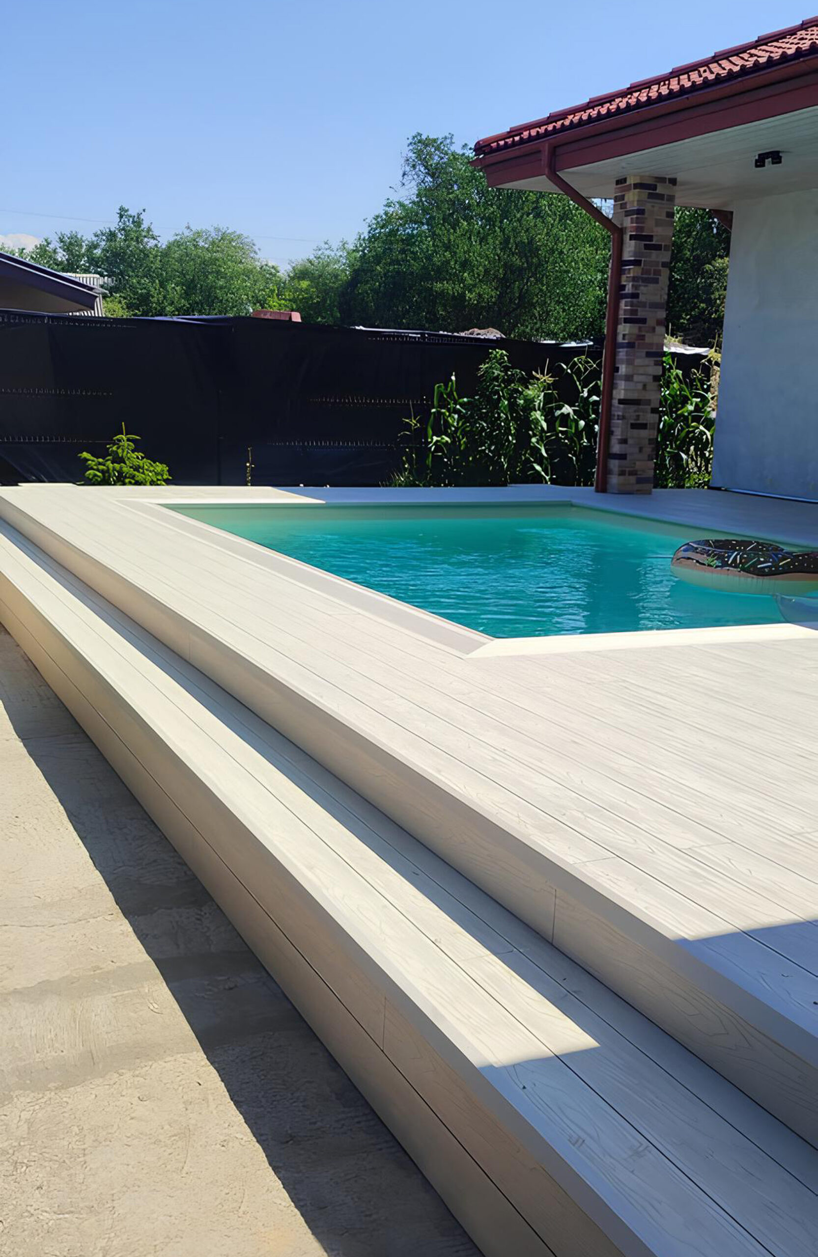 Light composite decking around a swimming pool with matching wide stairs