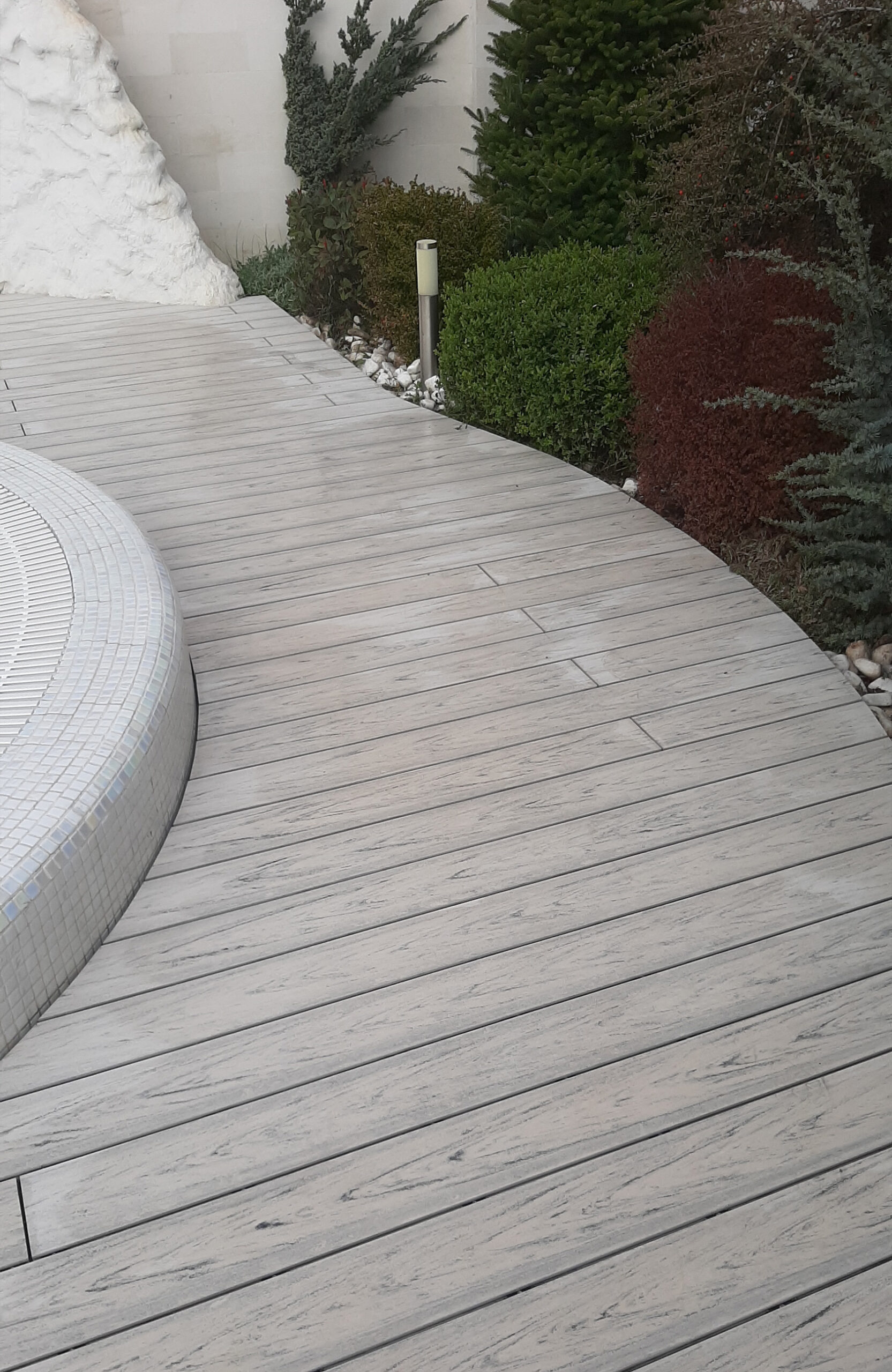 Smoke White composite decking for a landscaped pool area with curved edges
