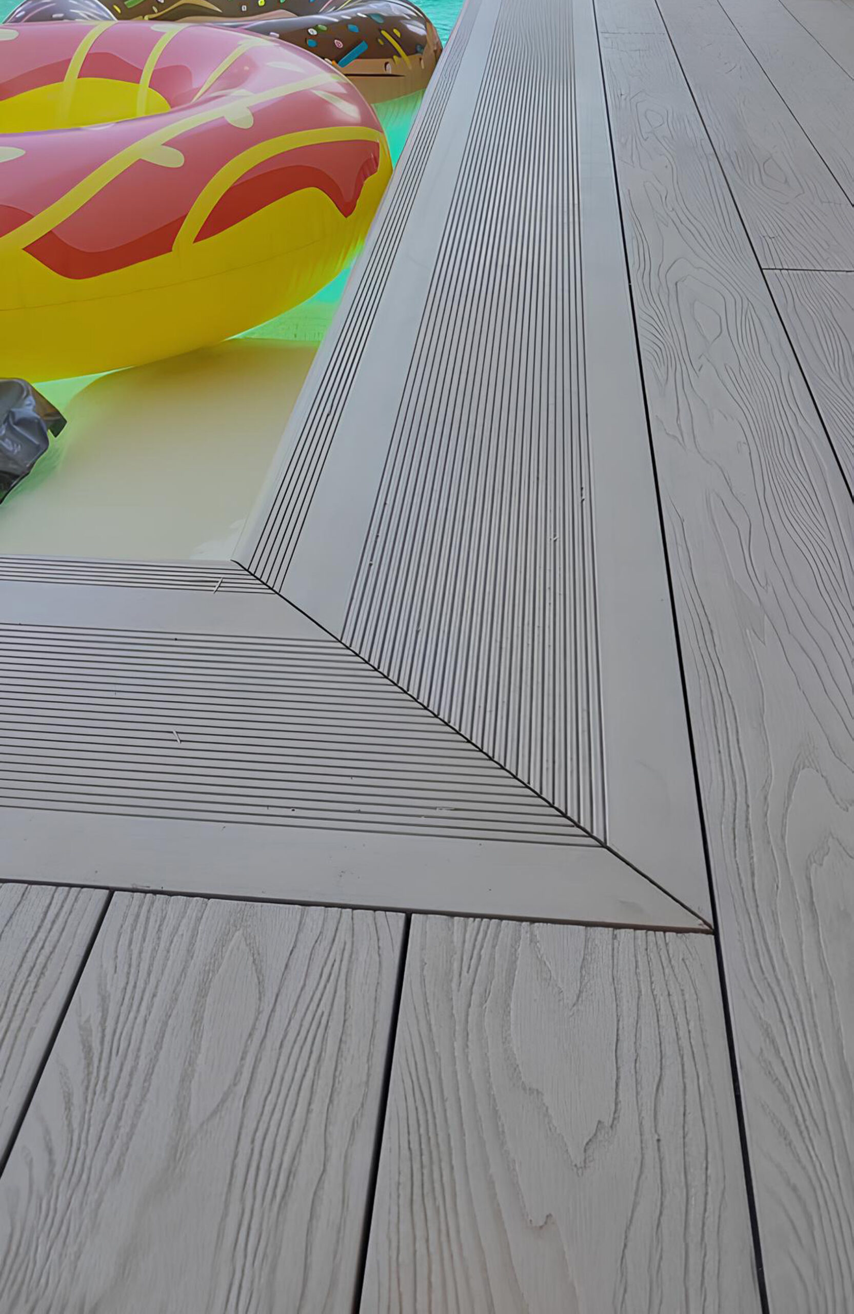 Light composite decking around a swimming pool with matching wide stairs