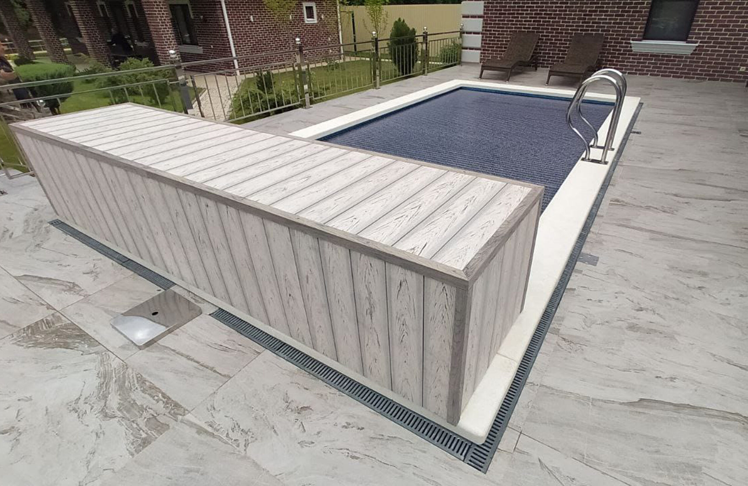 Light wood-effect BRUGGAN decking used for a spacious terrace and pool surround