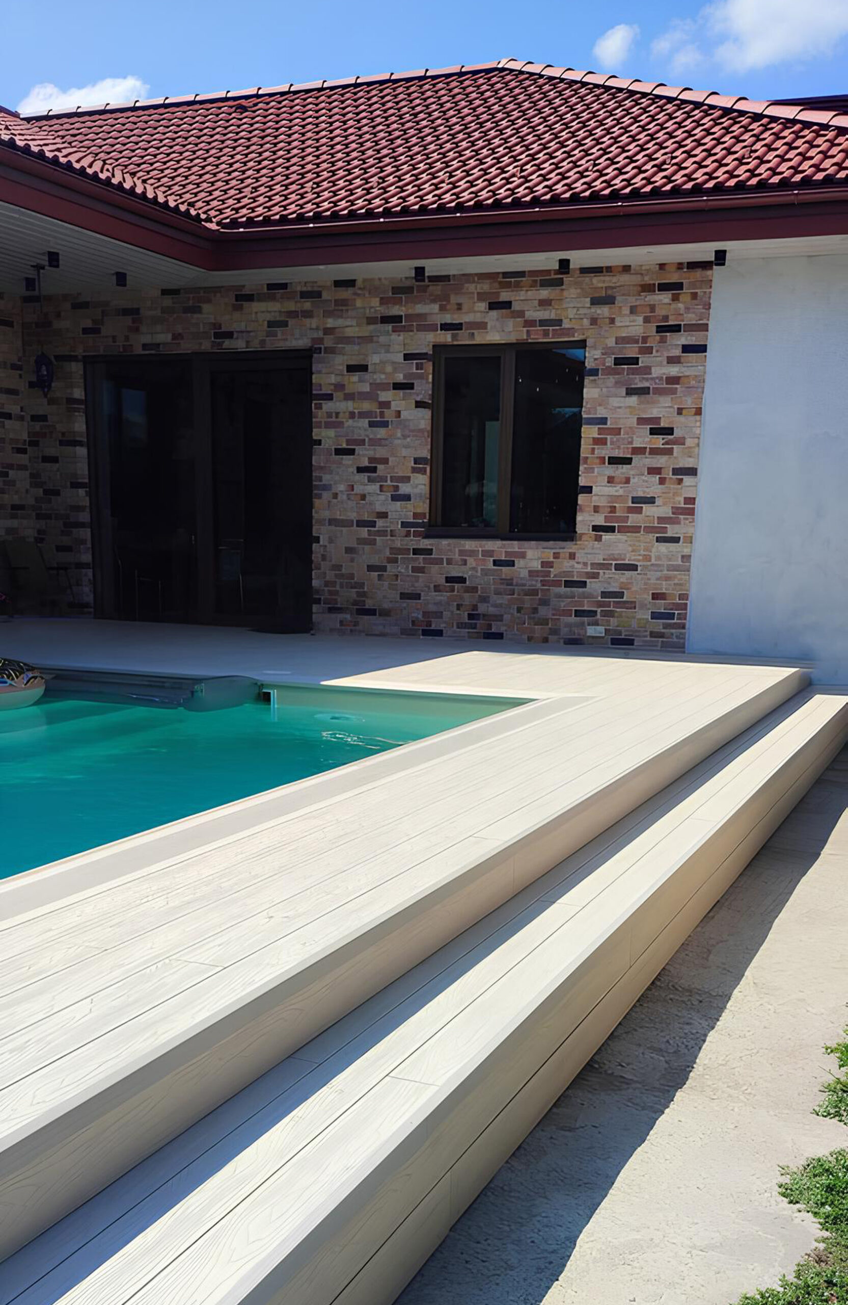 Light composite decking around a swimming pool with matching wide stairs