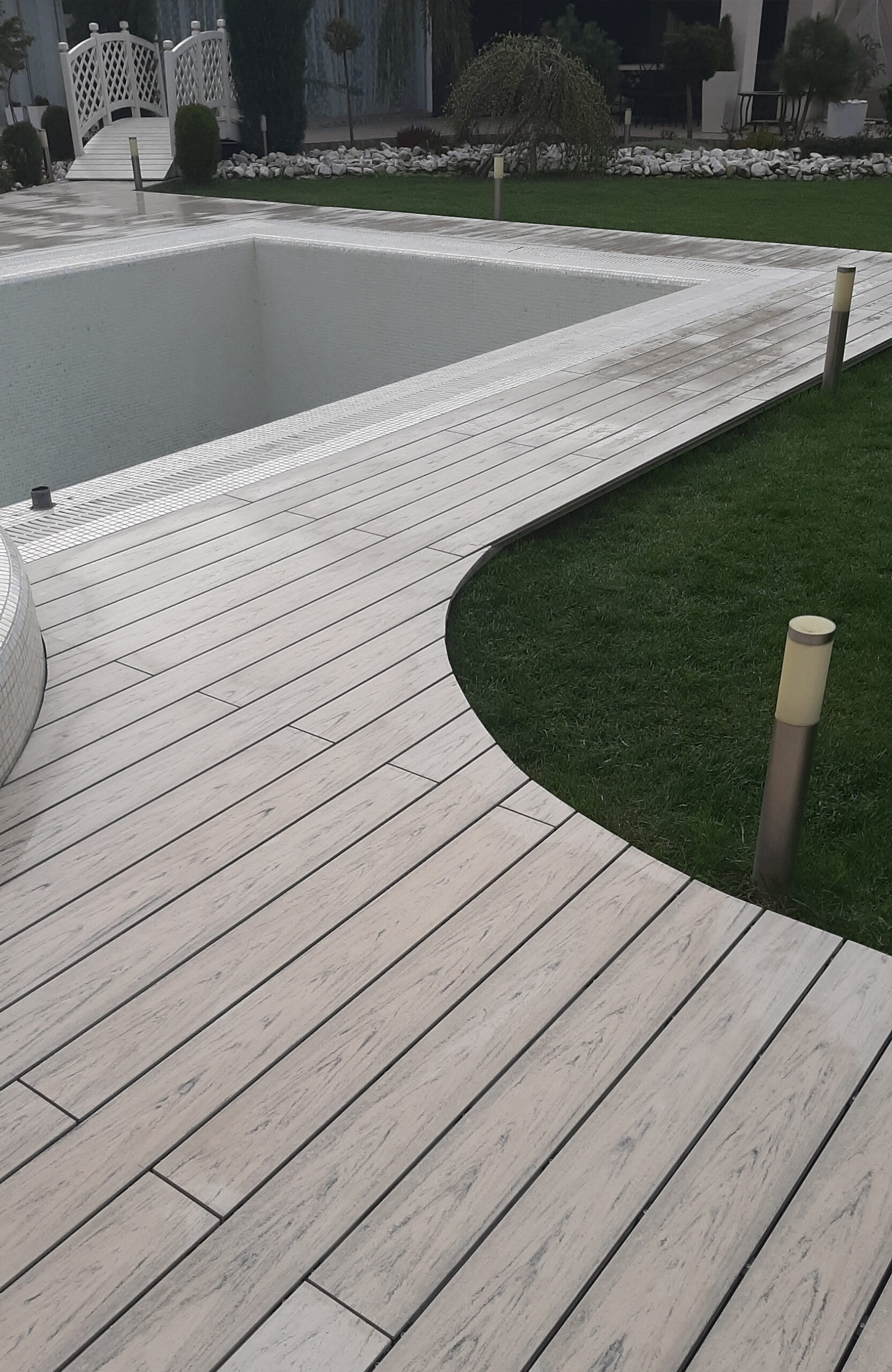 Smoke White composite decking for a landscaped pool area with curved edges
