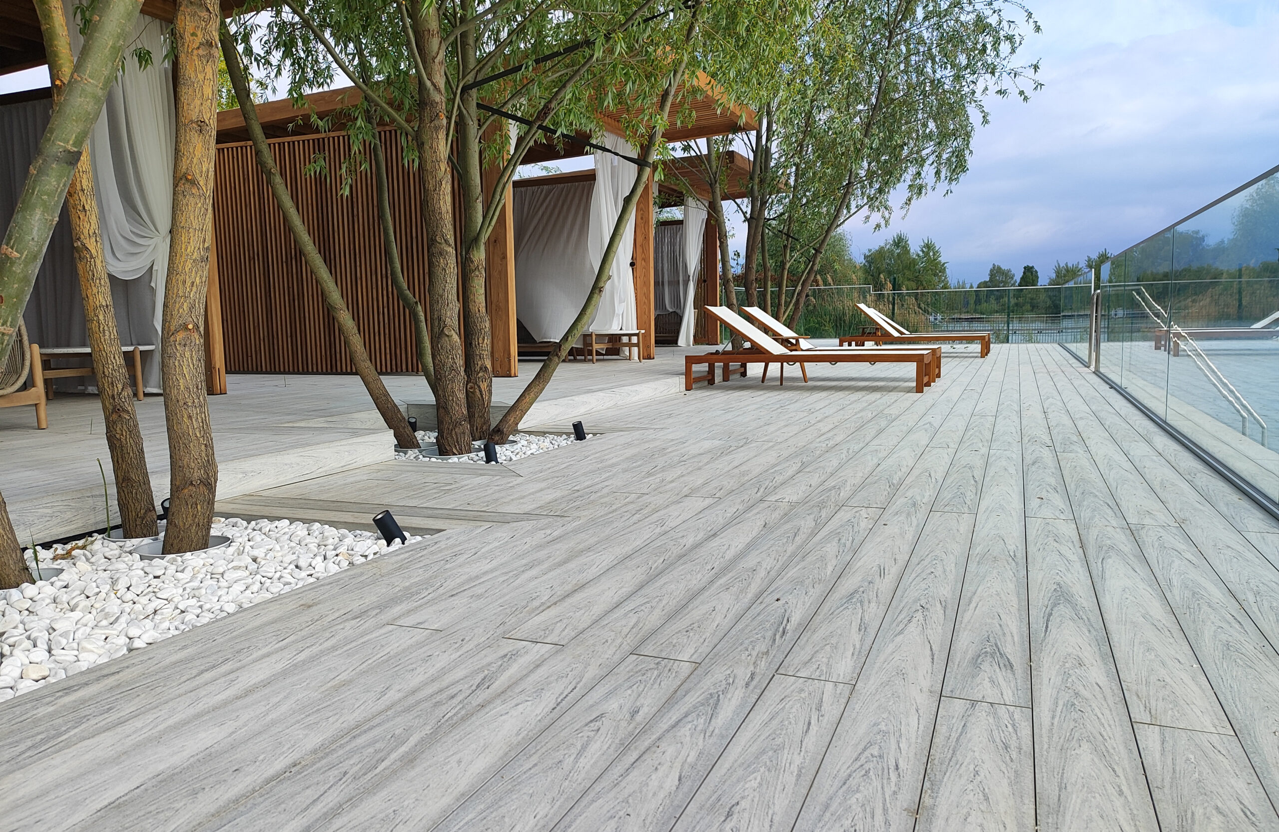 Modern lakeside terrace with light composite decking, lounge areas and glass railing