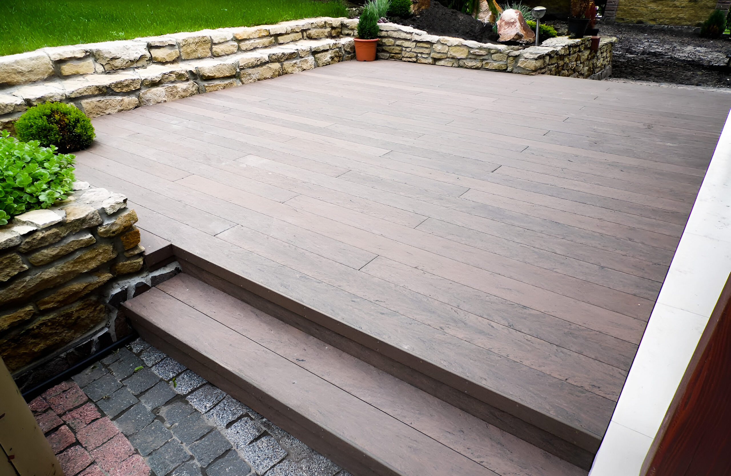 Garden terrace finished with BRUGGAN Multicolor Wenge decking and decorative stone landscaping