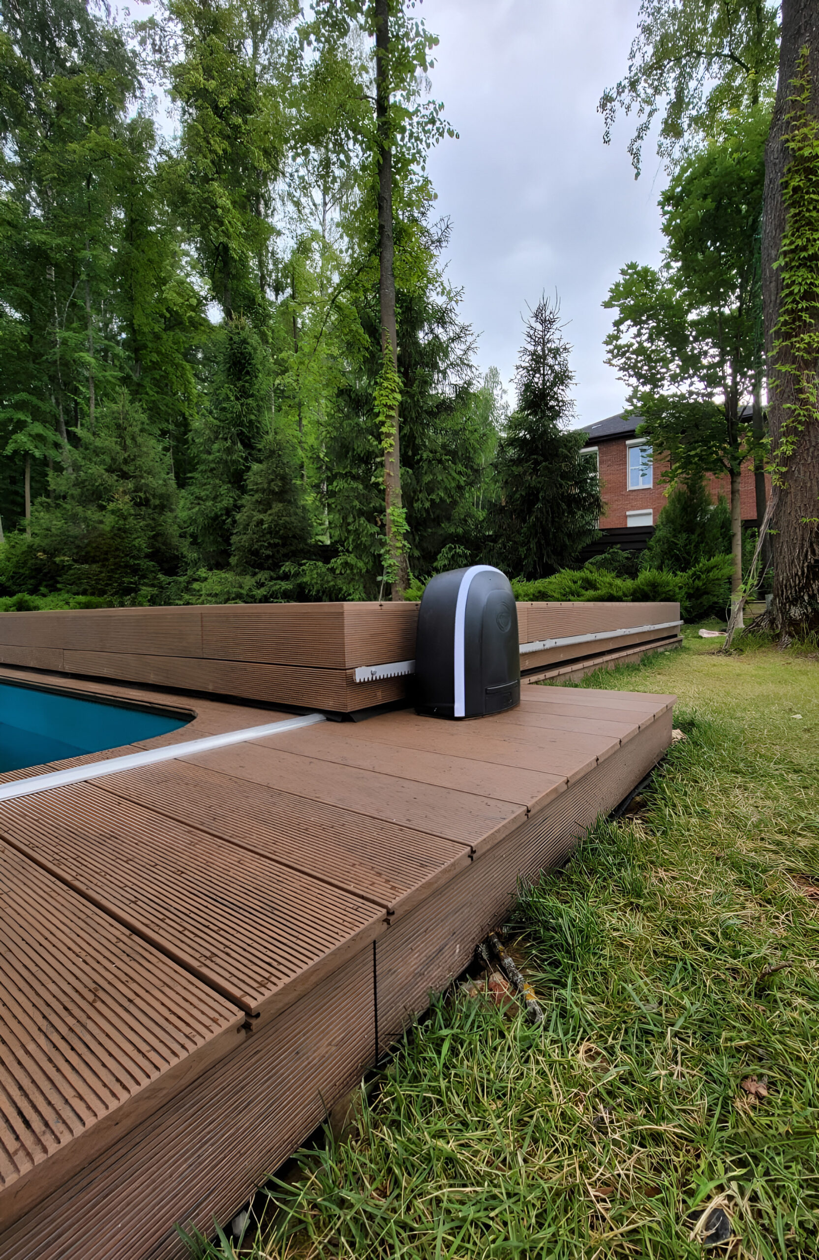 Private garden swimming pool with BRUGGAN Multicolor Wenge decking and sliding pool cover