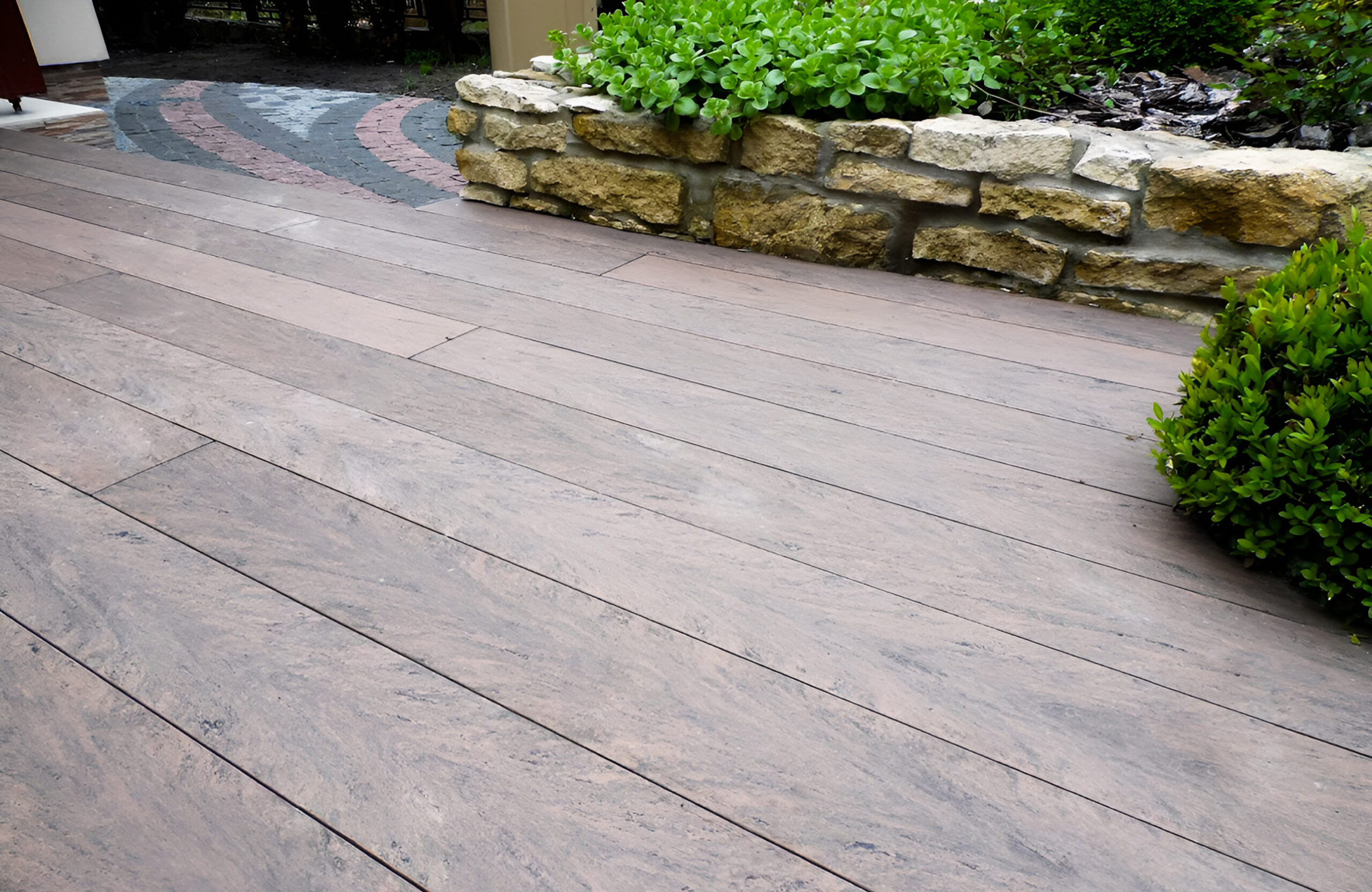 Garden terrace finished with BRUGGAN Multicolor Wenge decking and decorative stone landscaping