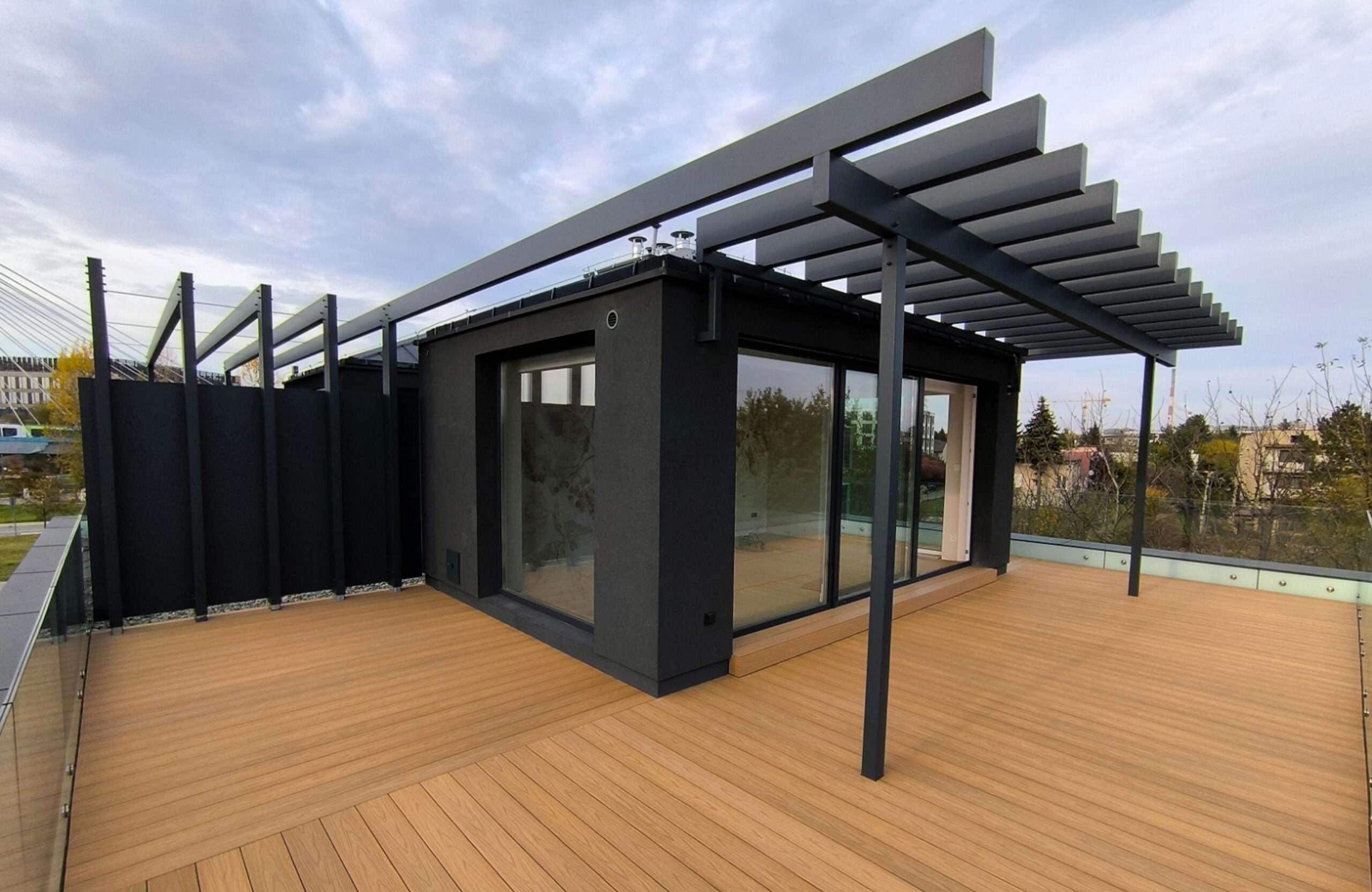 Legro Maple composite decking on a modern rooftop terrace with black pergola and glass railing