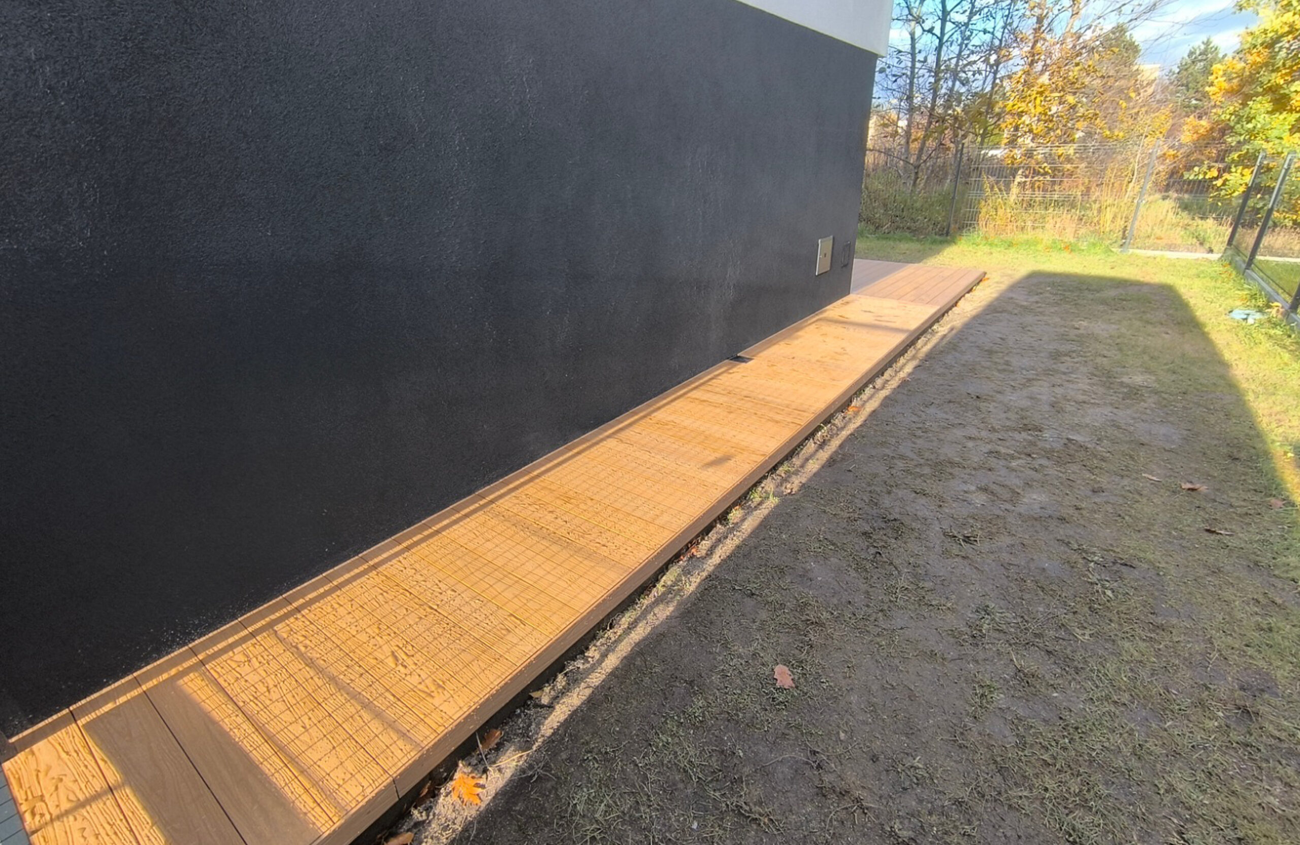 Legro Maple composite decking walkway along a modern house and garden