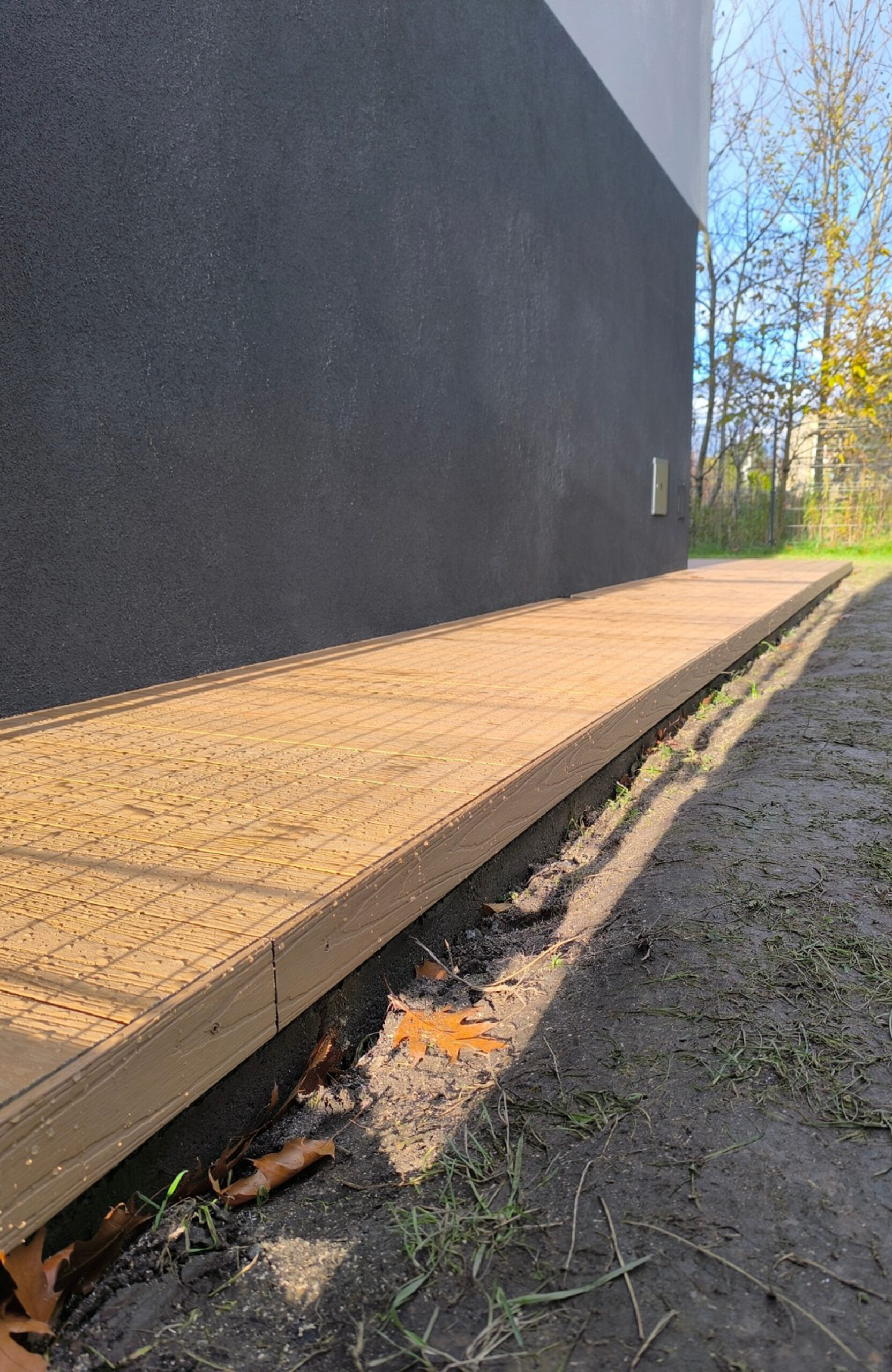 Legro Maple composite decking walkway along a modern house and garden