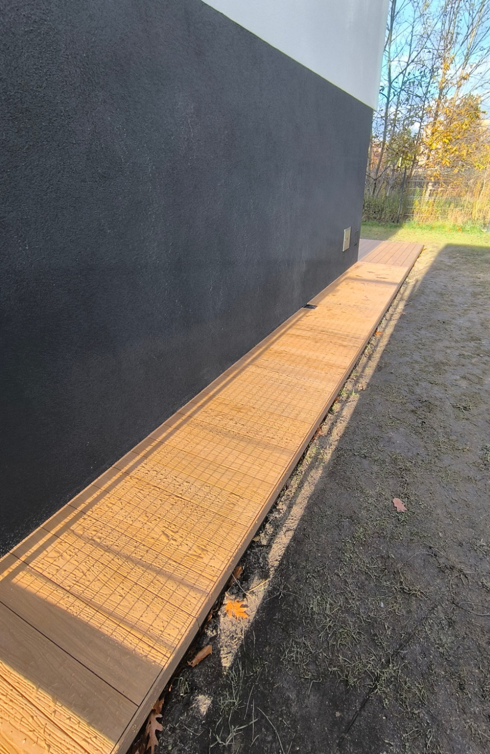 Legro Maple composite decking walkway along a modern house and garden