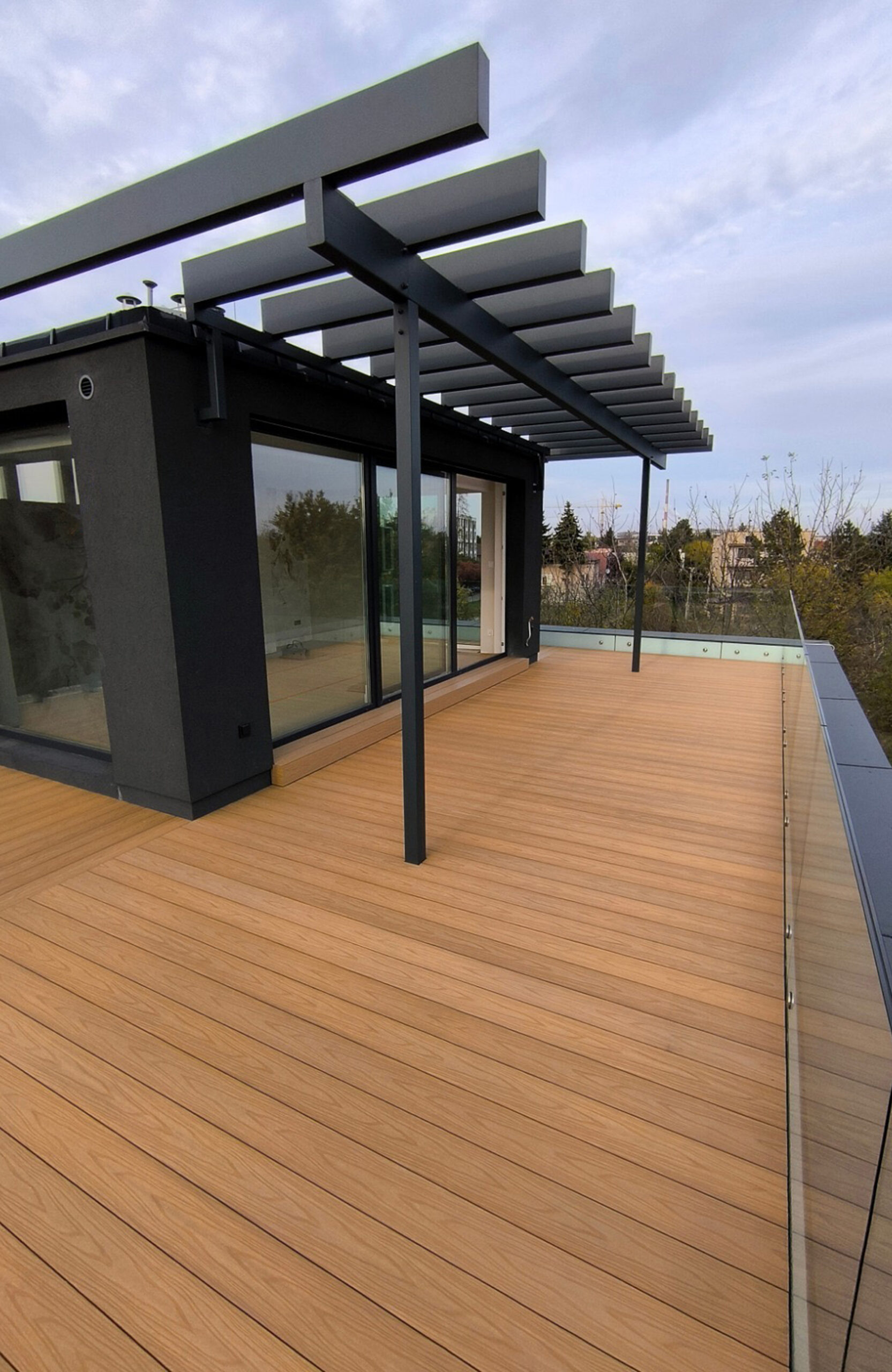 Legro Maple composite decking on a modern rooftop terrace with black pergola and glass railing