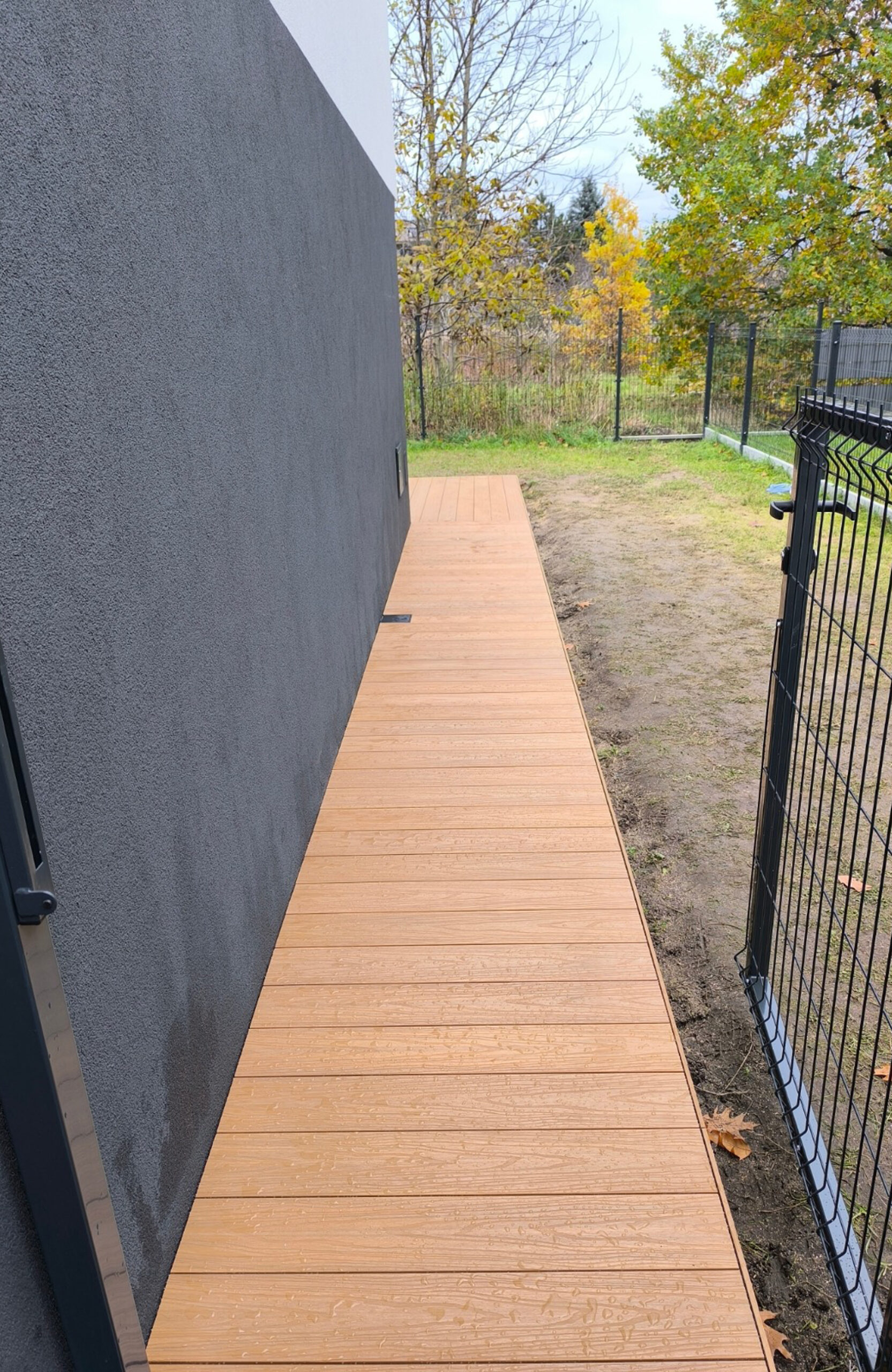 Legro Maple composite decking walkway along a modern house and garden