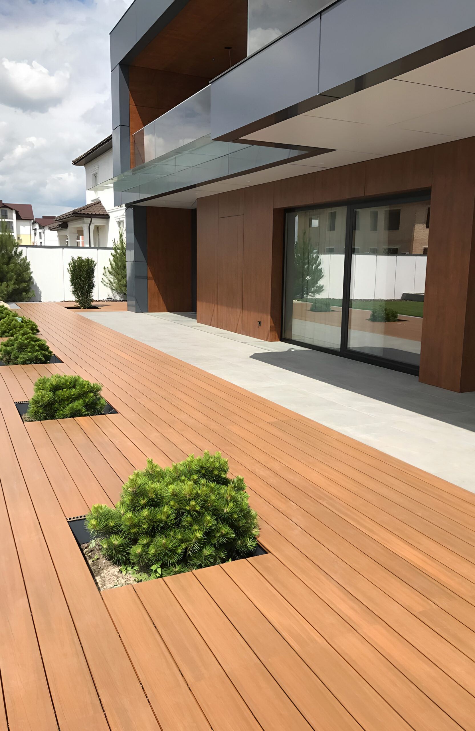 LEGRO teak composite decking around a modern house with integrated garden planters