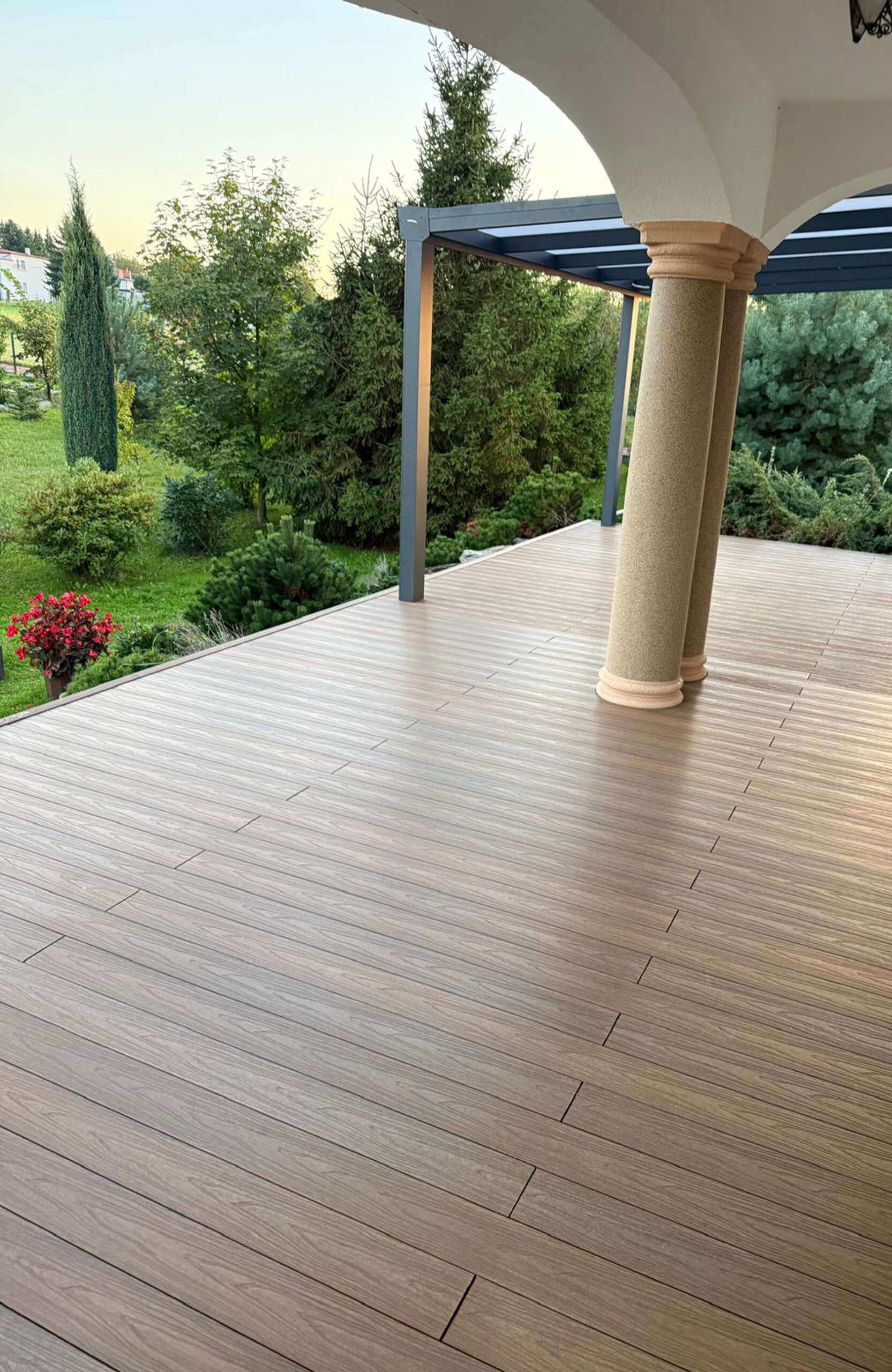 Durable and low-maintenance composite wood terrace decking installed on a home patio, featuring a realistic wood grain finish and a teak color