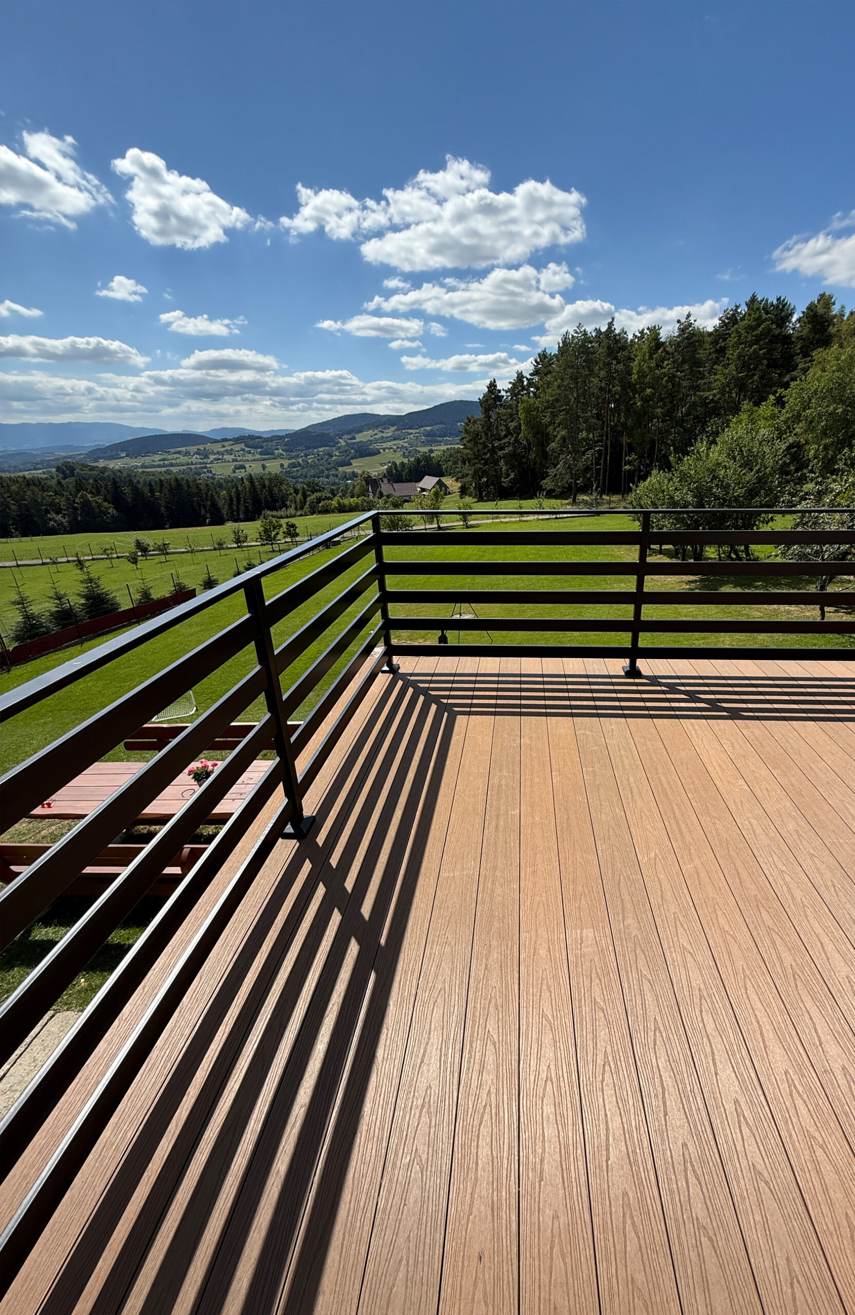 Elevated balcony view of a terrace with composite decking and a table overlooking a valley.