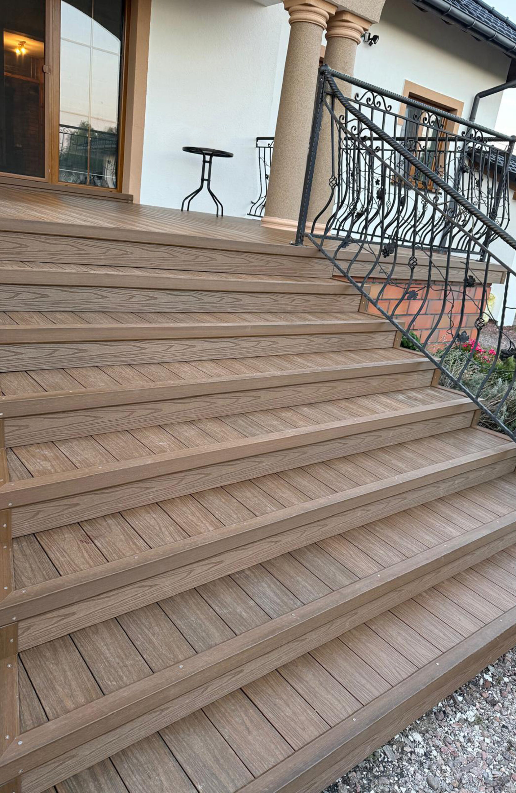 Anti-slip and weather-resistant composite wood stairs leading to a house entrance, showcasing the intricate wood grain texture and professional installation with matching fascia boards