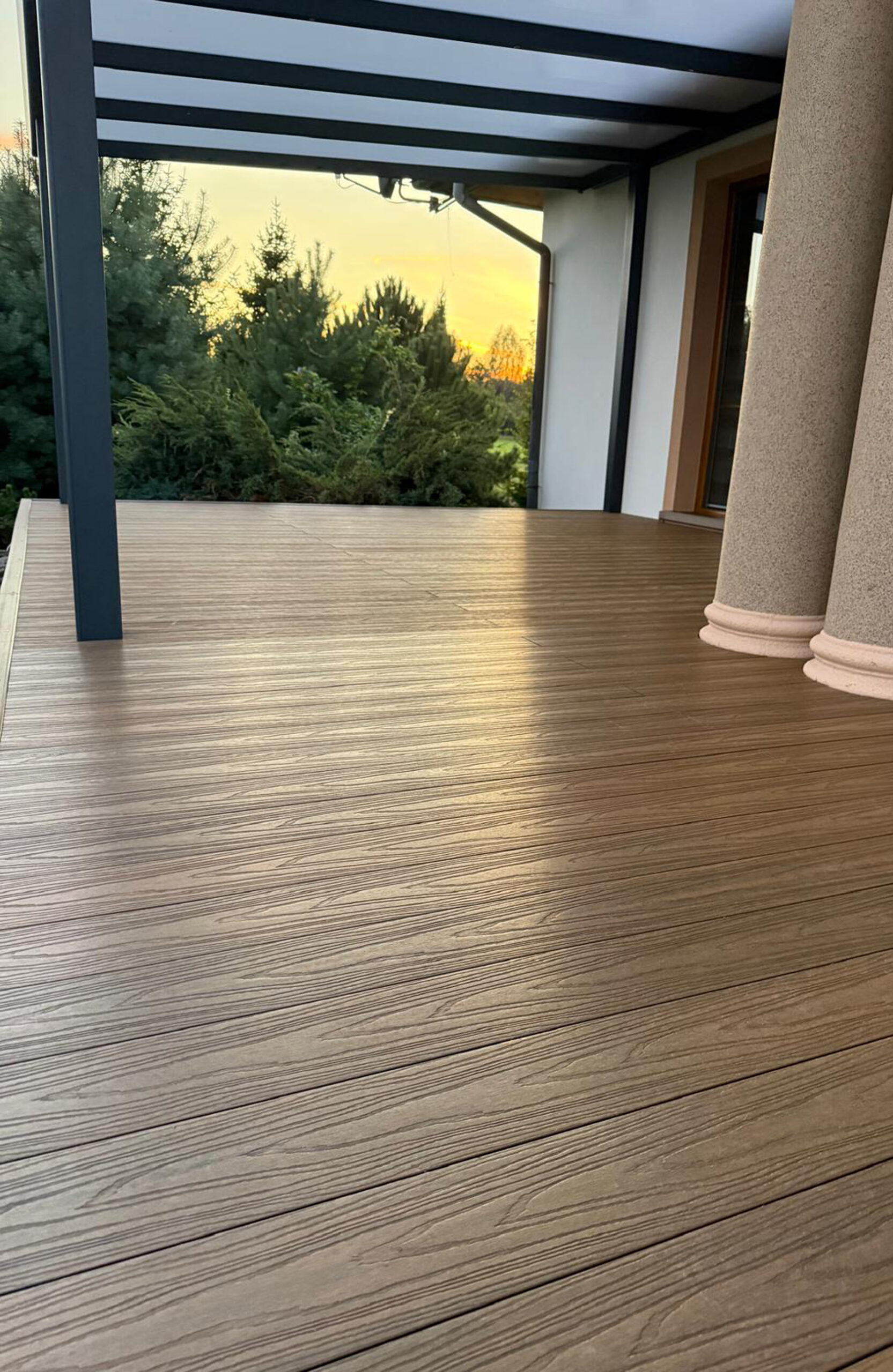 Durable and low-maintenance composite wood terrace decking installed on a home patio, featuring a realistic wood grain finish and a teak color