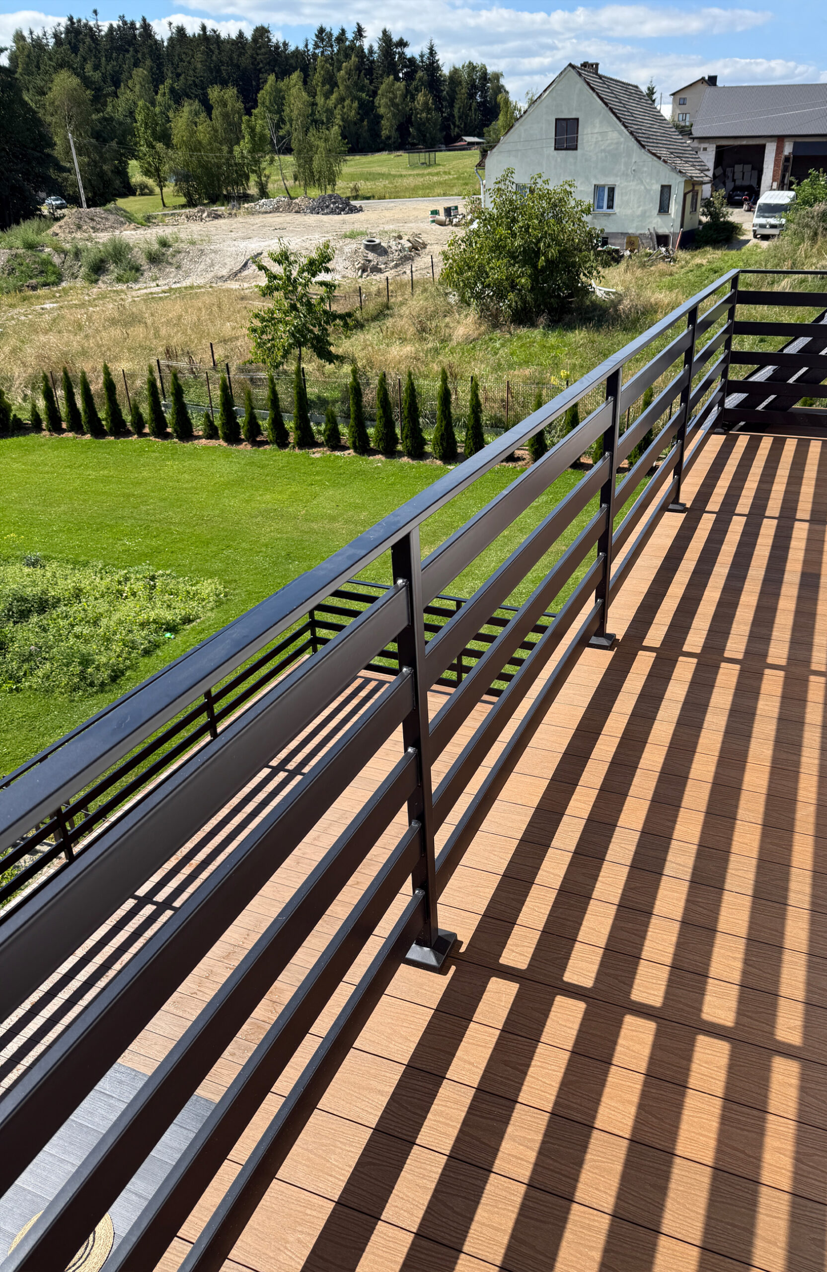 Elevated balcony view of a terrace with composite decking and a table overlooking a valley