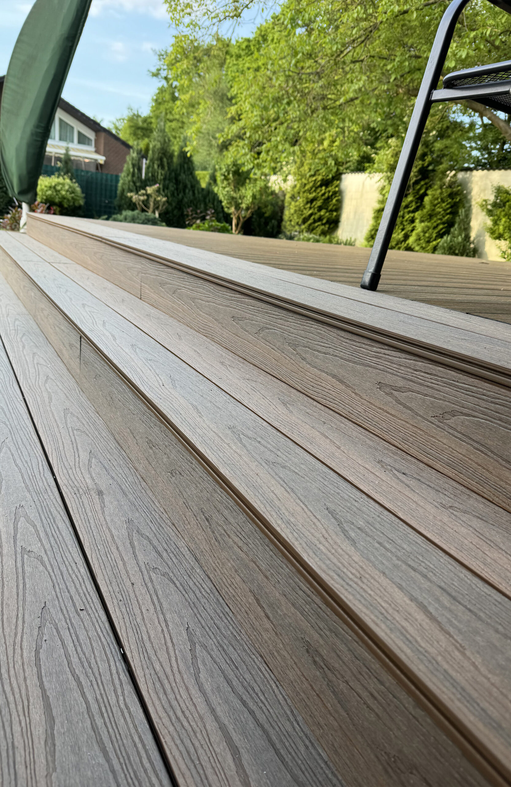 LEGRO teak WPC decking with wide composite steps overlooking a landscaped garden