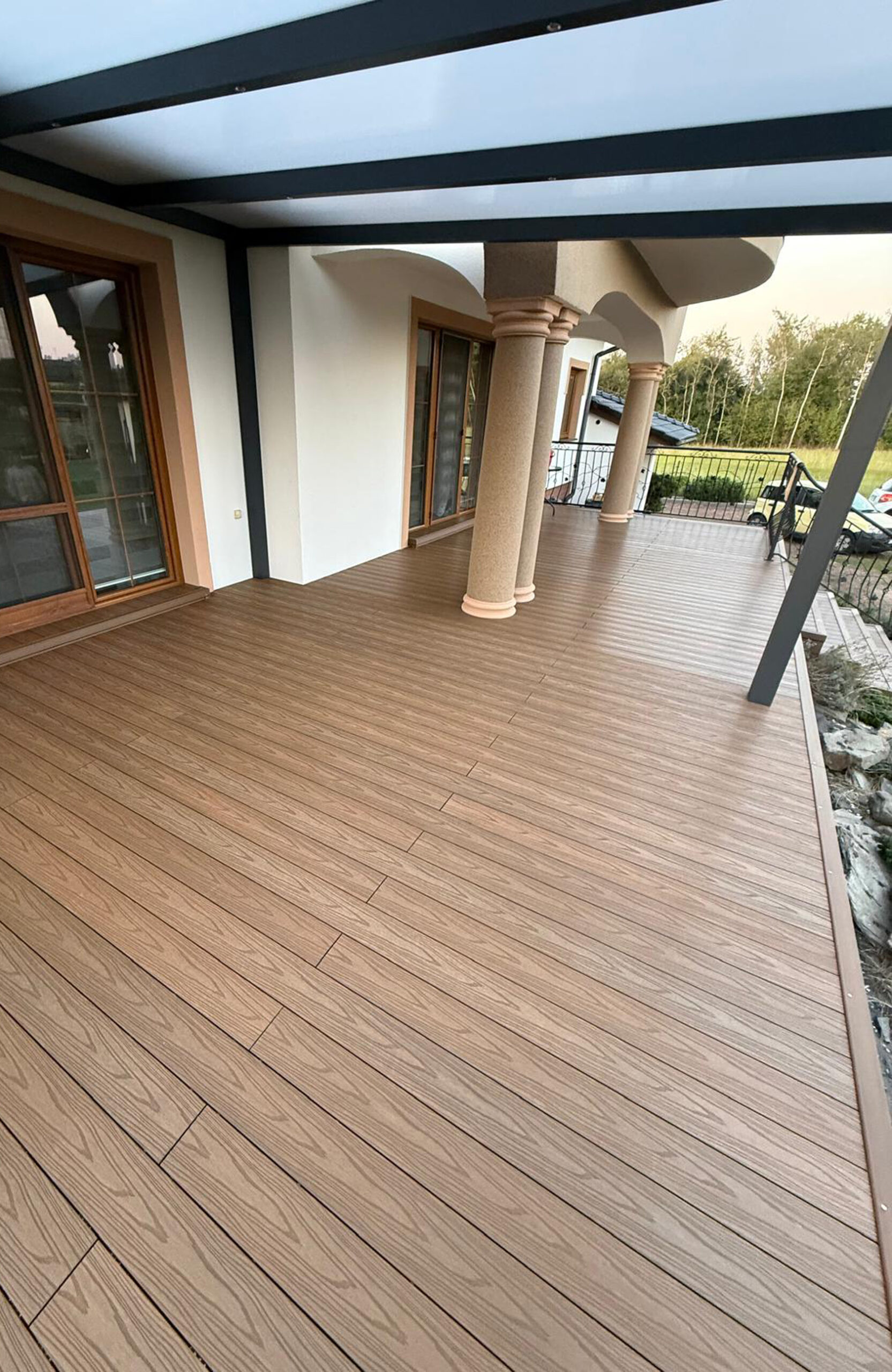 Durable and low-maintenance composite wood terrace decking installed on a home patio, featuring a realistic wood grain finish and a teak color