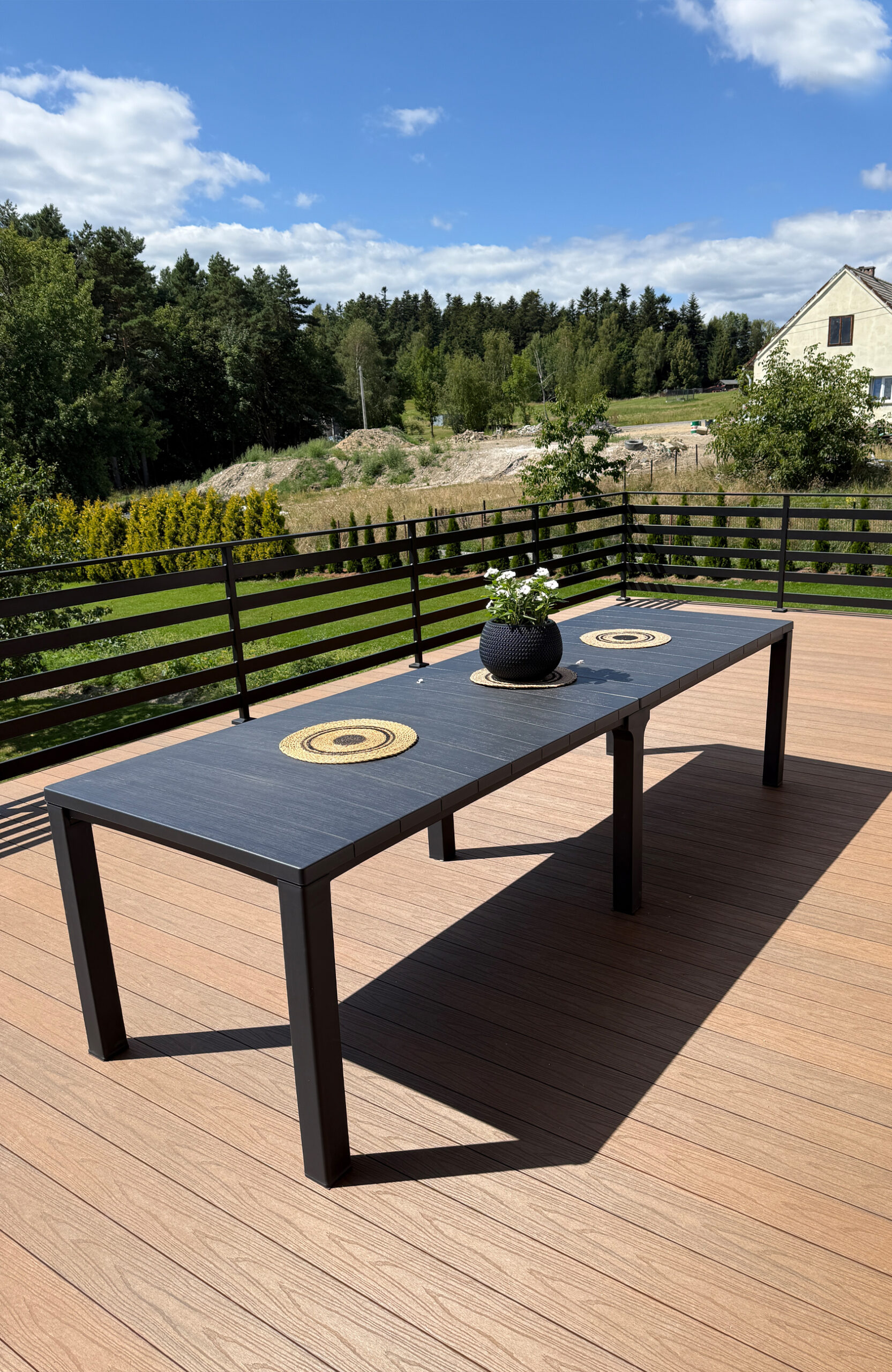 Close-up of a composite wood deck with a table and a view of rolling green hills.