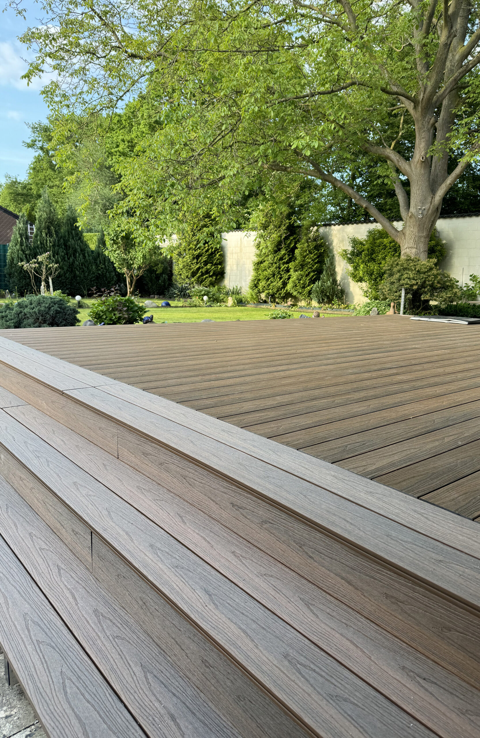 LEGRO teak WPC decking with wide composite steps overlooking a landscaped garden