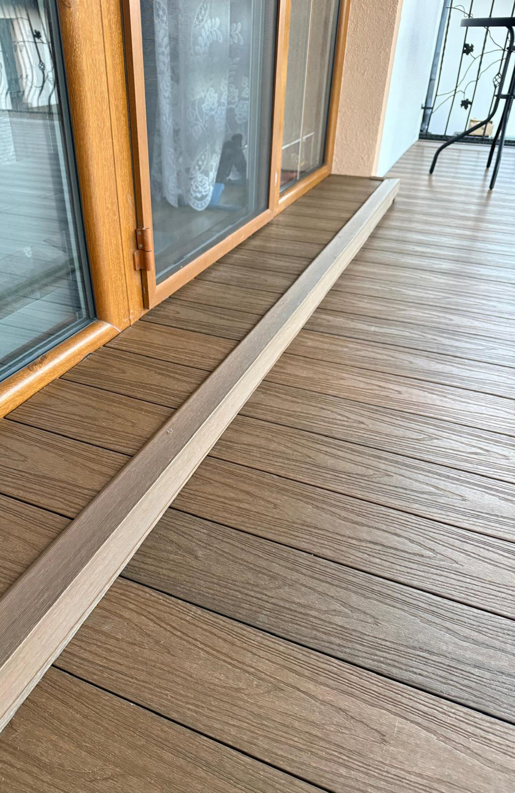 Durable and low-maintenance composite wood terrace decking installed on a home patio, featuring a realistic wood grain finish and a teak color