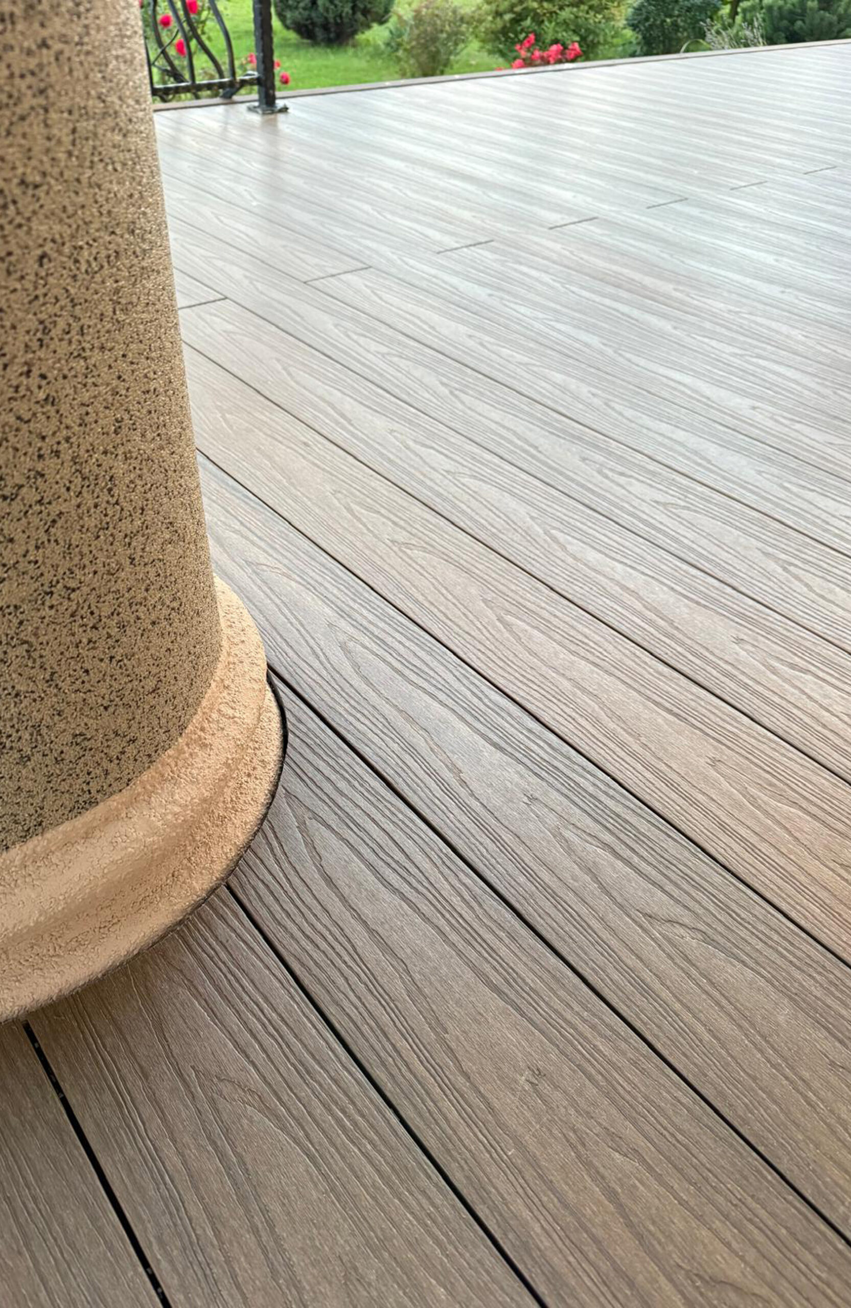 Durable and low-maintenance composite wood terrace decking installed on a home patio, featuring a realistic wood grain finish and a teak color